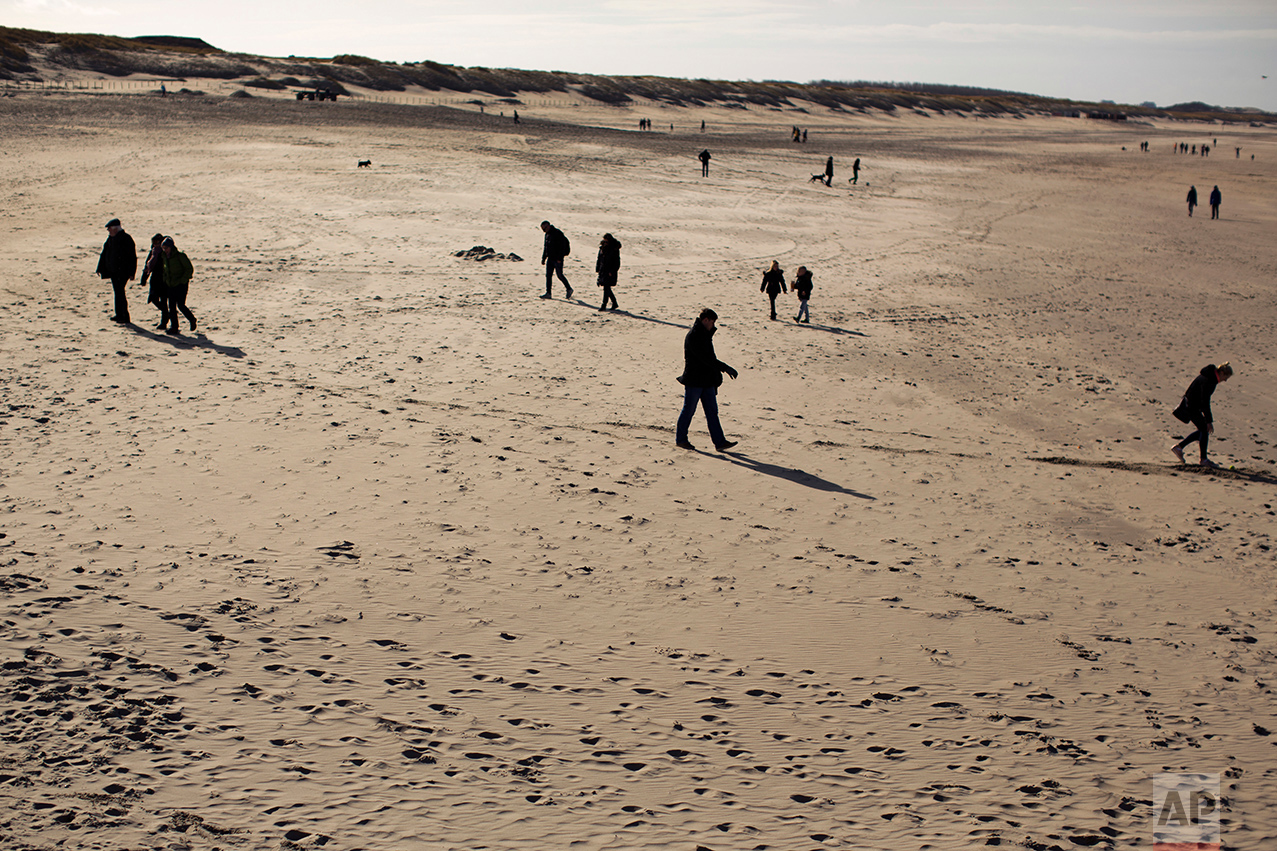 In this Sunday, March 5, 2017 photo, people walk along the beach in The Hague, The Netherlands. Of The Netherlands' 17 million people, just over one in five now have a migrant background _ rising to roughly half-and-half in The Netherlands' four largest melting-pot cities: Amsterdam, Rotterdam, Utrecht and The Hague. (AP Photo/Emilio Morenatti)