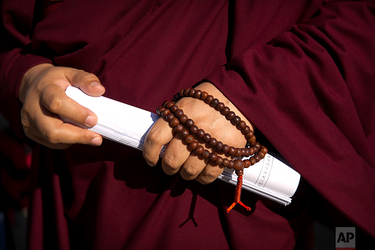In this Wednesday, March 8, 2017 photo, a Tibetan delegate wears prayer beads and carries rolled-up paperwork as he arrives for a plenary session of China's National People's Congress (NPC) at the Great Hall of the People in Beijing. (AP Photo/Mark Schiefelbein)