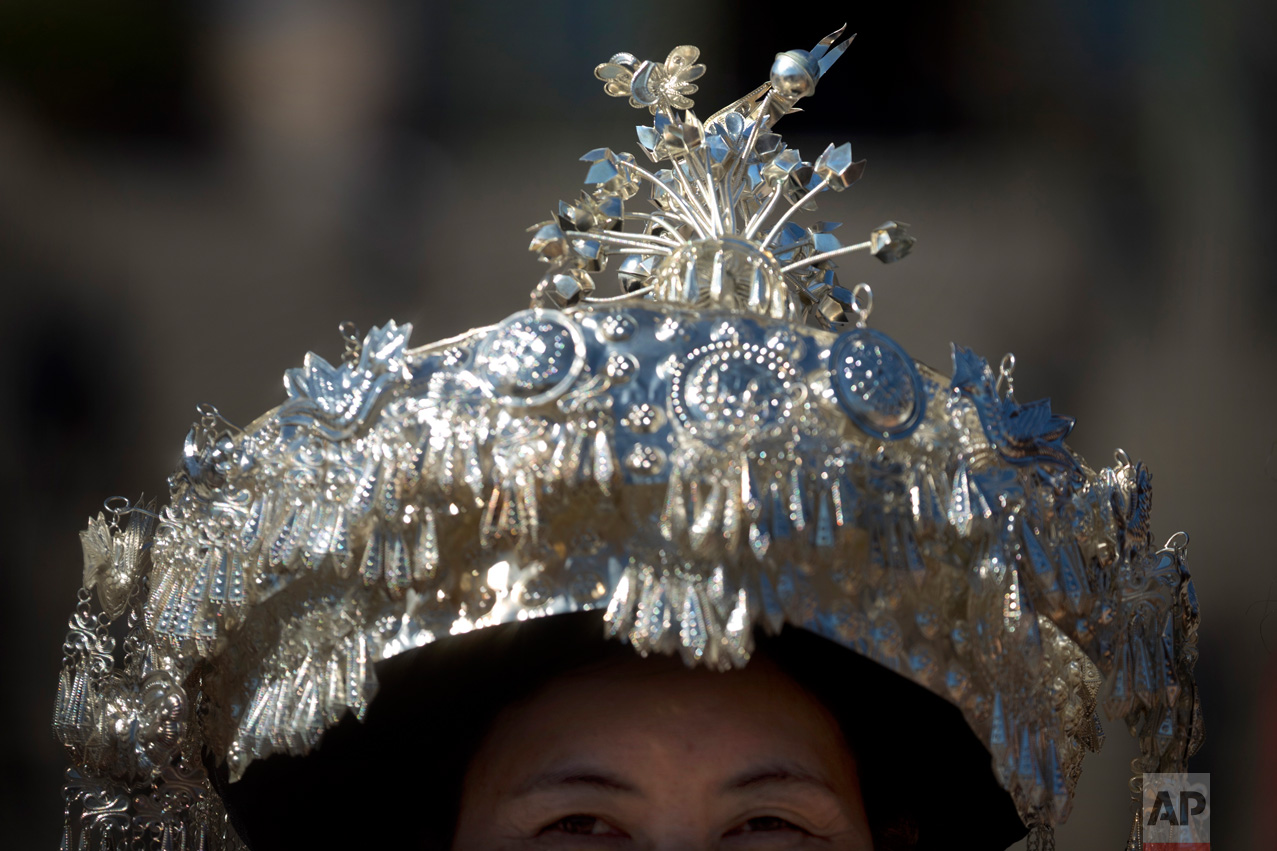 In this Sunday, March 12, 2017 photo, an ethnic minority delegate wears a hat topped with a silver bird as she leaves a plenary session of China's National People's Congress (NPC) at the Great Hall of the People in Beijing. (AP Photo/Mark Schiefelbein)