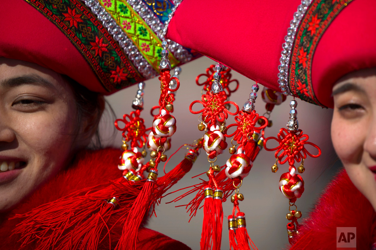 In this Sunday, March 12, 2017 photo, decorations hang from the hats of hospitality staff members as they pose for a group photo during a plenary session of the National People's Congress (NPC) in Beijing. (AP Photo/Mark Schiefelbein)