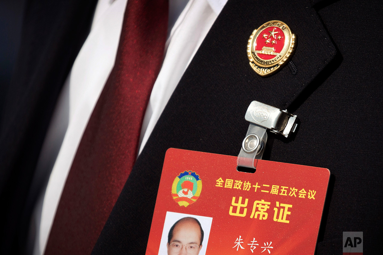In this Friday, March 10, 2017 photo, a member of China's procuratorate wears a pin on his lapel as he arrives to hear a report by the head of China's Supreme People's Procuratorate during a plenary session of the Chinese People's Political Consultative Congress (CPPCC) in Beijing. (AP Photo/Mark Schiefelbein)
