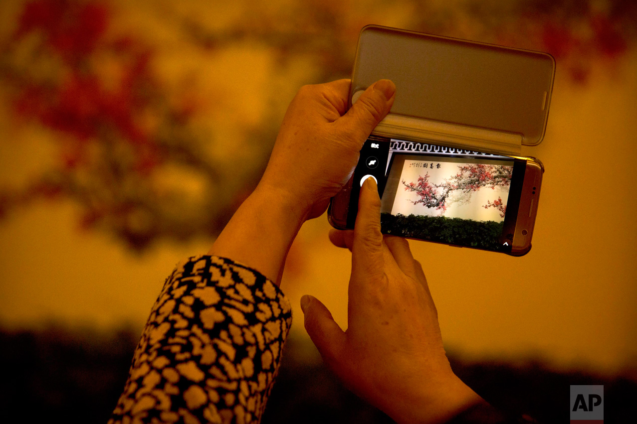 In this Friday, March 10, 2017 photo, a delegate takes a smartphone photo of a painting inside the Great Hall of the People during a plenary session of the Chinese People's Political Consultative Congress (CPPCC) in Beijing. (AP Photo/Mark Schiefelbein)