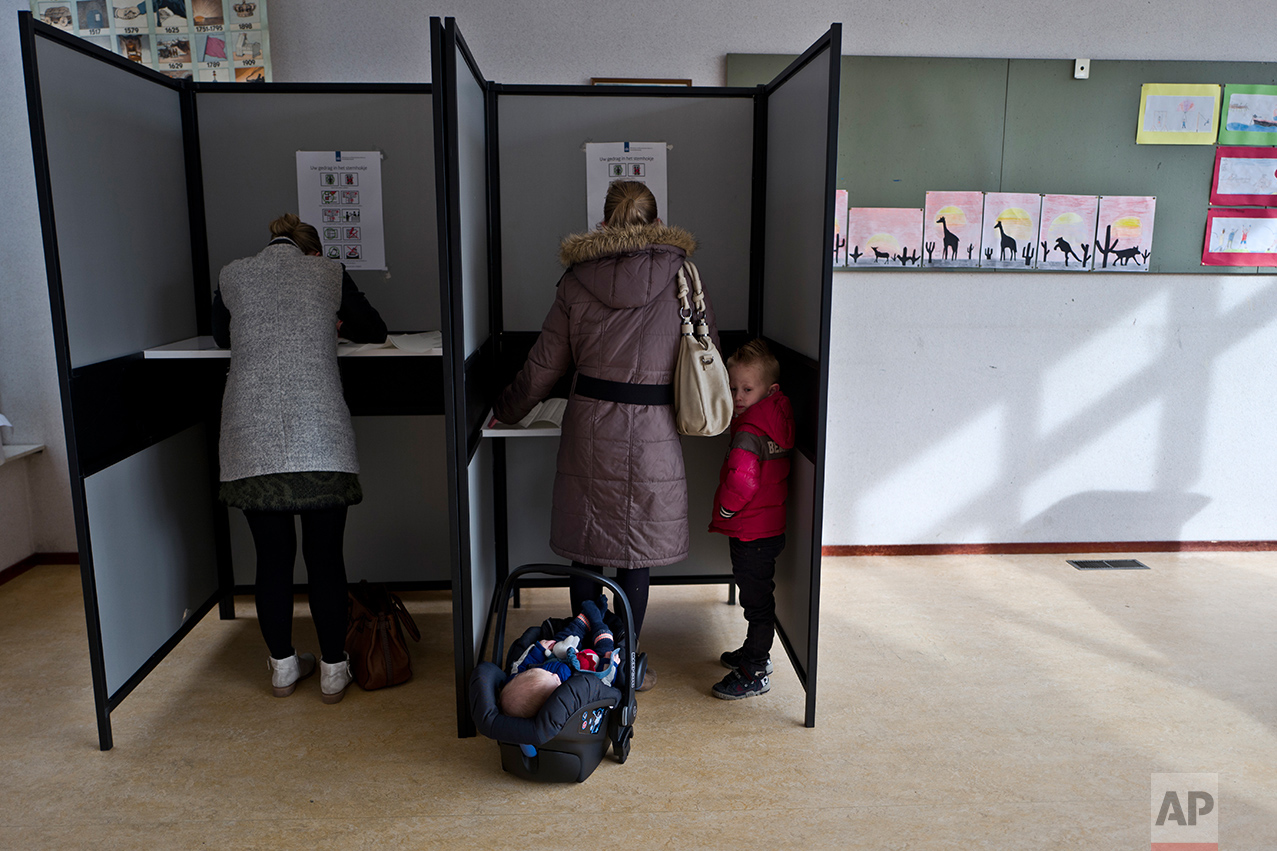  A boy stands next to his mother as she fills out her ballot prior to casting her vote for the Dutch general elections at a polling station set up in a school in Staphorst, Netherlands, Wednesday, March 15, 2017. (AP Photo/Muhammed Muheisen) 