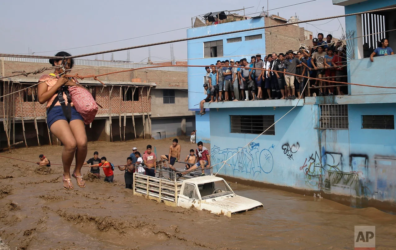 A woman is pulled to safety in a zip line harness in Lima, Peru, on Friday, March 17, 2017. Intense rains and mudslides over the previous few days have wrought havoc around the Andean nation and caught residents in Lima, a desert city of 10 million where it almost never rains, by surprise. (AP Photo/Martin Mejia)