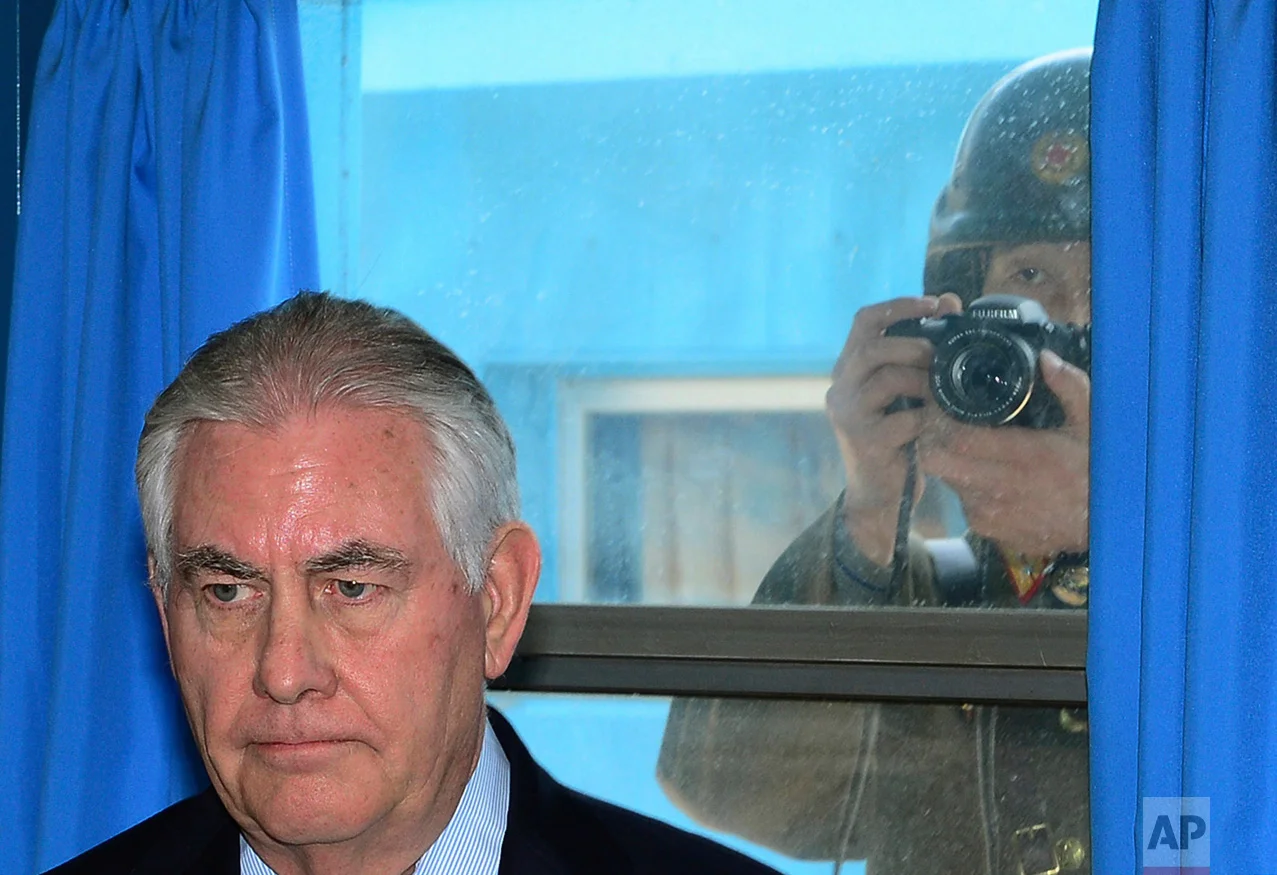 A North Korean soldier, right, tries to take a photograph through a window while U.S. Secretary of State Rex Tillerson visits the U.N. Command Military Armistice Commission meeting room Friday, March 17, 2017, in the border village of Panmunjom, which has separated South and North Korea since the Korean War. Tillerson on Friday visited the world's most heavily armed border, greeting U.S. soldiers on guard near the tense buffer zone between rivals North and South Korea. (Korea Pool/Yonhap via AP)