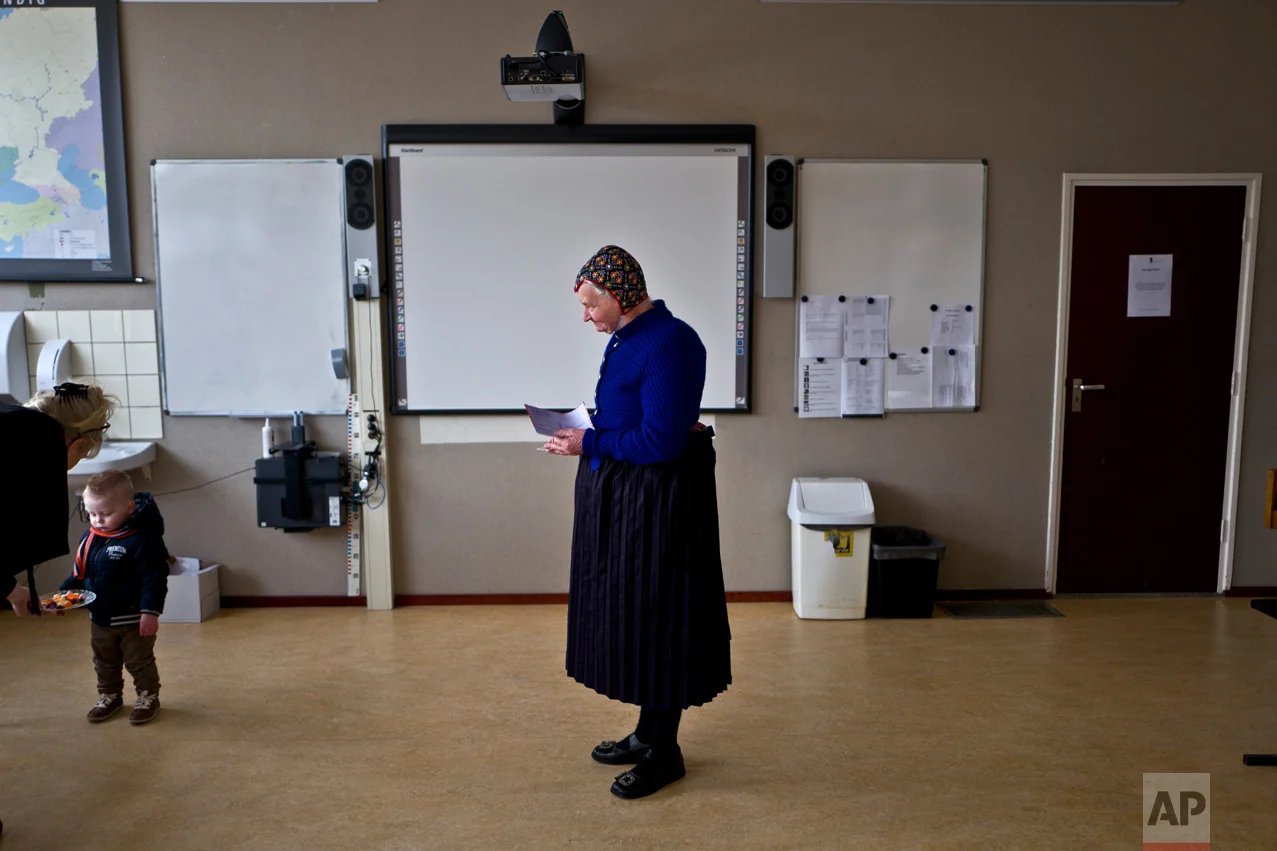 An elderly woman wearing a traditional hat waits her turn to cast her vote for the Dutch general elections at a polling station in a school in Staphorst, Netherlands, Wednesday, March 15, 2017. Mark Rutte, the Dutch prime minister who had pushed the electorate through five years of tough economic measures, emerged victorious in a bruising battle with Geert Wilders, whose relentless invective against all things Muslim and anything from the European Union failed to earn him the breakthrough that many had come to count on as a given. (AP Photo/Muhammed Muheisen)
