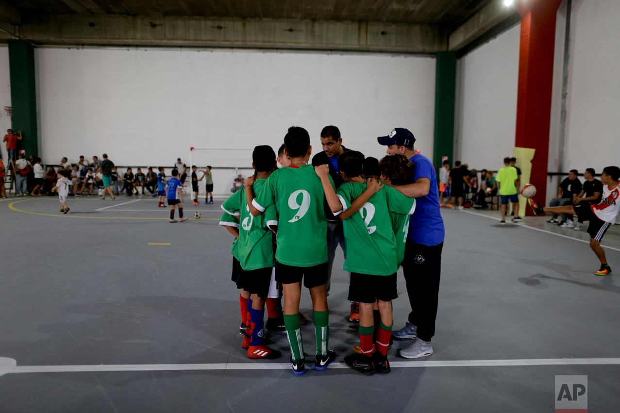 In this March 18, 2017 photo, Club Social Parque players huddle with their coach before a match at the youth soccer academy Club Social Parque in a working class neighborhood of Buenos Aires, Argentina. The humble youth academy has perhaps produced more world-class players than any other. (AP Photo/Natacha Pisarenko)