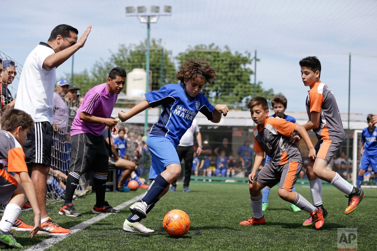 In this Nov. 19, 2016 photo, Thiago "Coco" Perugini controls the ball during a youth league game on the outskirts of in Buenos Aires, Argentina. "The day that he doesn't want to play anymore, it all ends right here. He has to be a good person and study and he has the support of his parents," said Thiago's dad, Diego Perugini, a former lower division soccer player who is a coach at Parque. (AP Photo/Natacha Pisarenko)