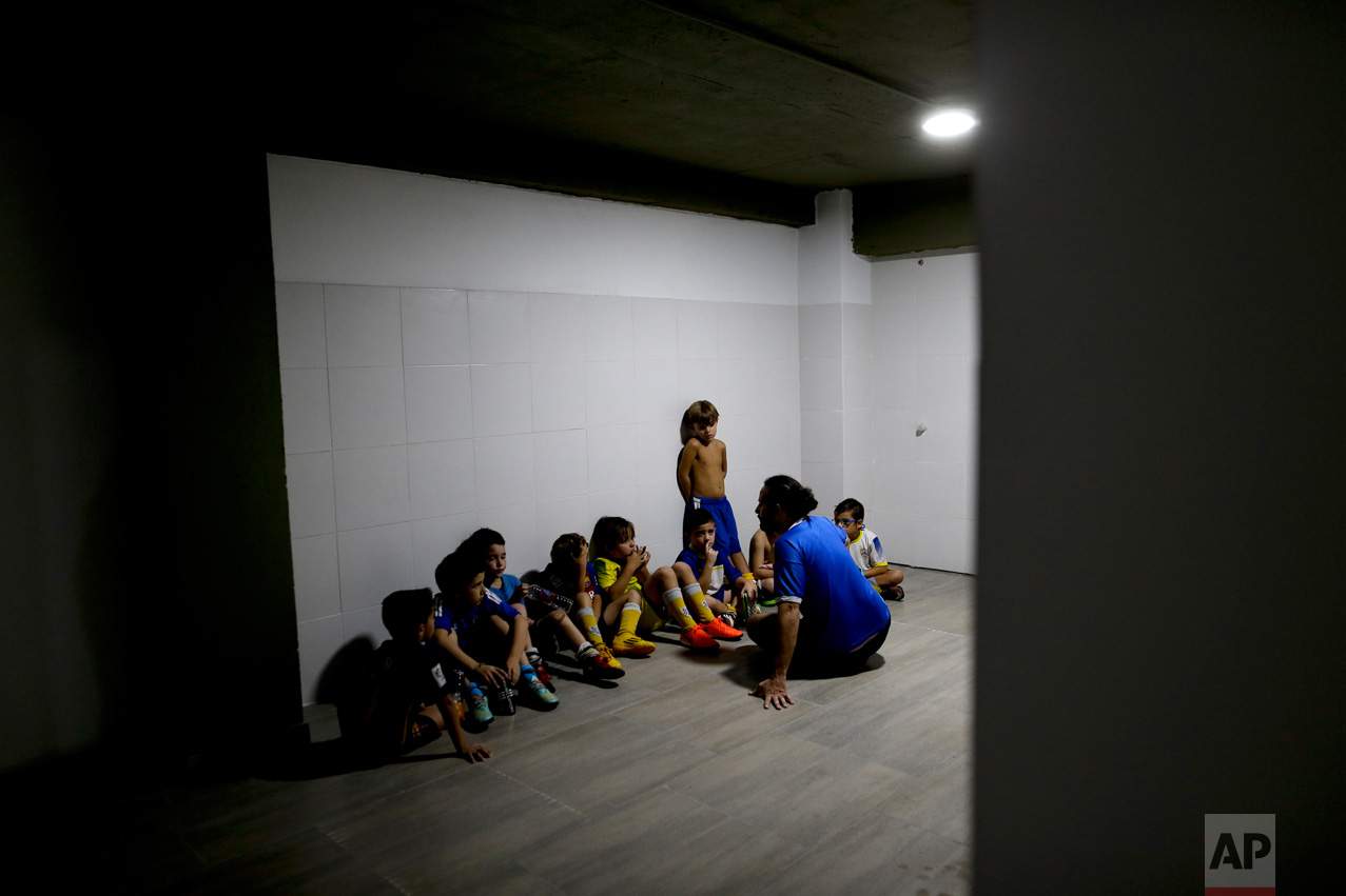 In this March 18, 2017 photo, coach Ariel Picallo talks to his team of 7-year-olds after they lost a game at the youth soccer academy Club Social Parque in a working class neighborhood of Buenos Aires, Argentina. At his youth soccer academy, about 150 children as young as 6 from all economic levels train together twice a week and compete on the weekends. (AP Photo/Natacha Pisarenko)