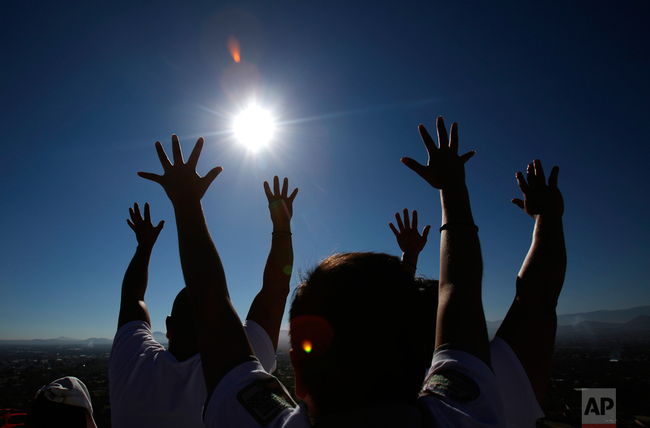 Family members celebrating the spring equinox raise their hands toward the sun atop the Pyramid of the Sun at the Teotihuacan archeological site in Mexico, on Tuesday, March 21, 2017 Although the official vernal equinox occurred on Monday, thousands of visitors were expected to climb the ancient pyramid on Tuesday to greet the sun and celebrate the beginning of spring. (AP Photo/Rebecca Blackwell)