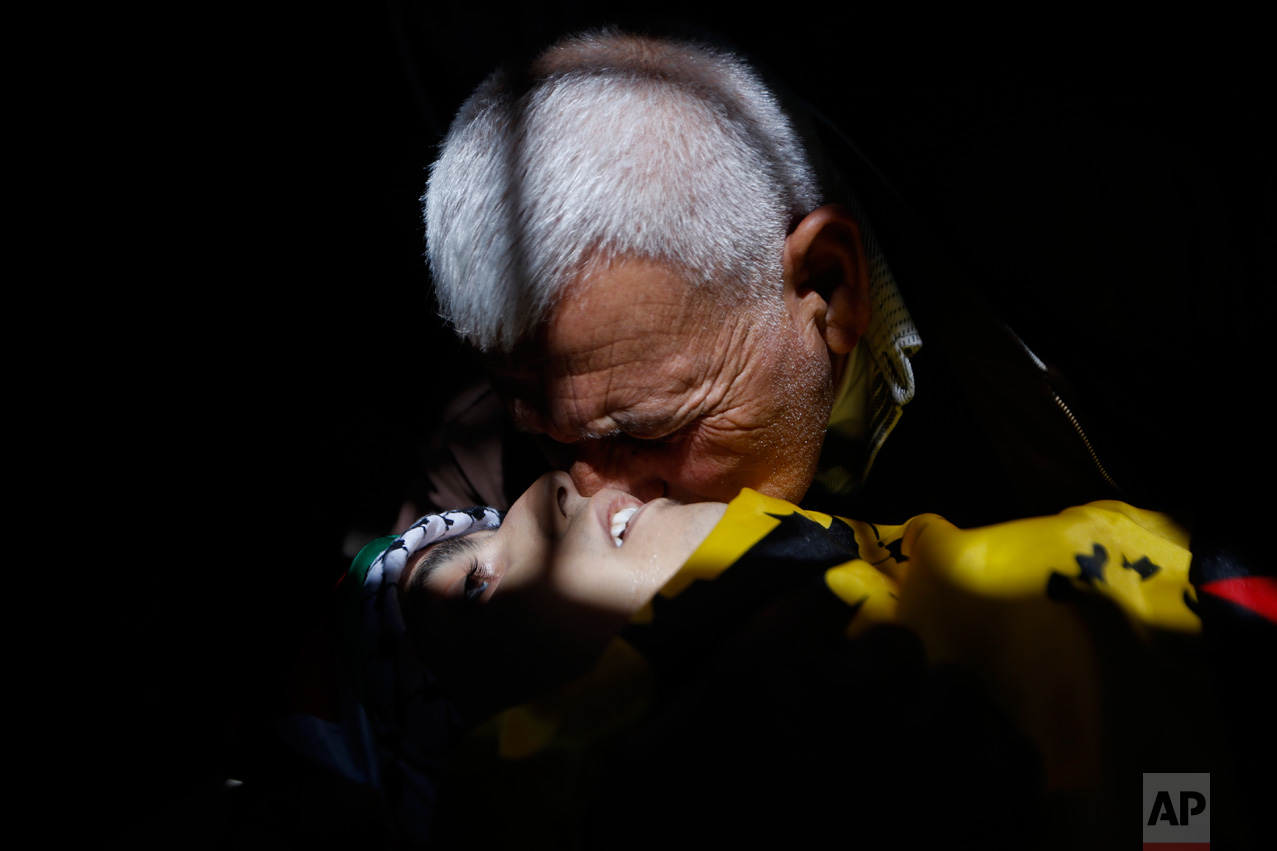 A relative kisses the cheek of 17-year old Palestinian Mahmoud Hattab during his funeral at the Jalazoun refugee camp near the West Bank city of Ramallah, Friday, March 24, 2017. The Palestinian Health Ministry said Israeli troops killed the teenager and wounded another three when soldiers opened fire on their vehicle in the West Bank. The Israeli military said the men had stopped near a Jewish settlement and "hurled fire bombs" at the community, and the soldiers fired at the attackers who fled the scene in their vehicle. (AP Photo/Majdi Mohammed)