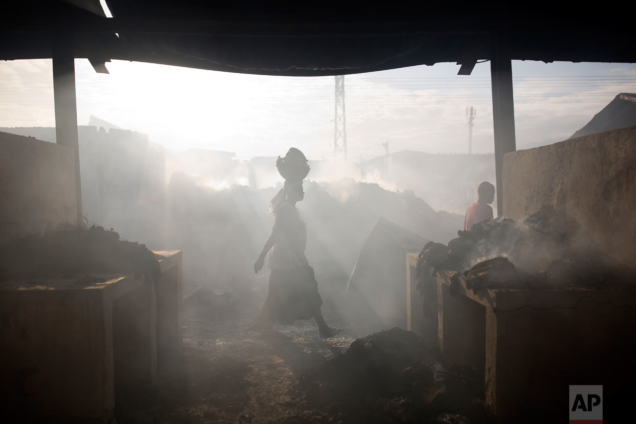 A merchant walks through smoke at a market in Port-au-Prince, Haiti, on Monday, March 20, 2017. A fire damaged the biggest central market in the center of the Haitian capital. (AP Photo/Dieu Nalio Chery)