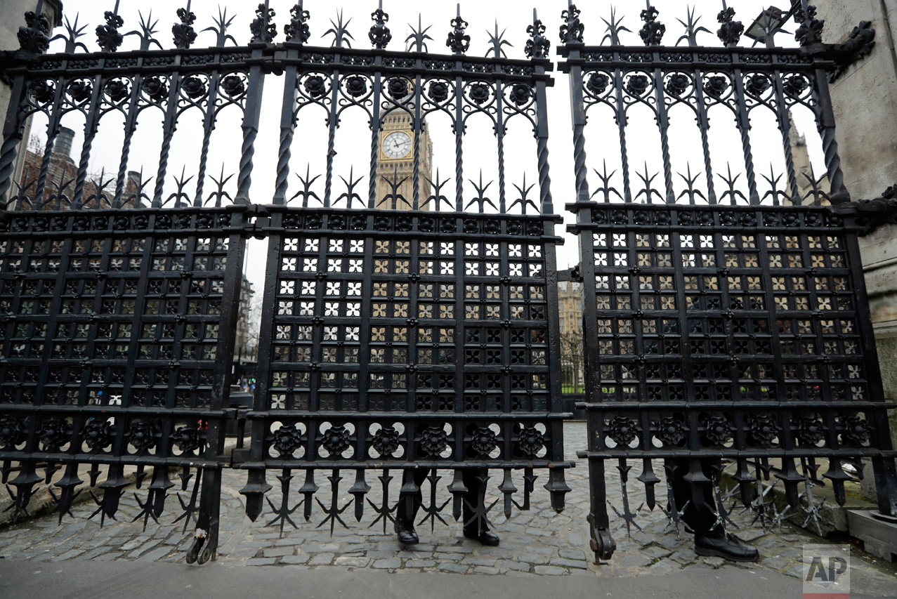 Police officers adjust a panel on a gate outside the Houses of Parliament in London, Friday, March 24, 2017. On Thursday authorities identified a 52-year-old Briton as the man who mowed down pedestrians and stabbed a policeman to death outside Parliament, saying he had a long criminal record and once was investigated for extremism — but was not currently on a terrorism watch list. (AP Photo/Matt Dunham)