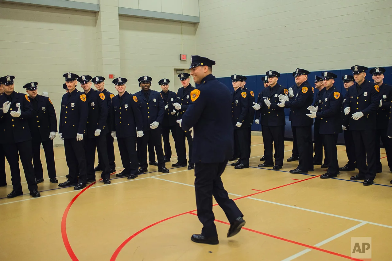 Matias Ferreira, center, arrives as his colleagues salute him while they prepare to march during their graduation from the Suffolk County Police Department Academy at the Health, Sports and Education Center in Suffolk, Long Island, New York, Friday, March 24, 2017. (AP Photo/Andres Kudacki)