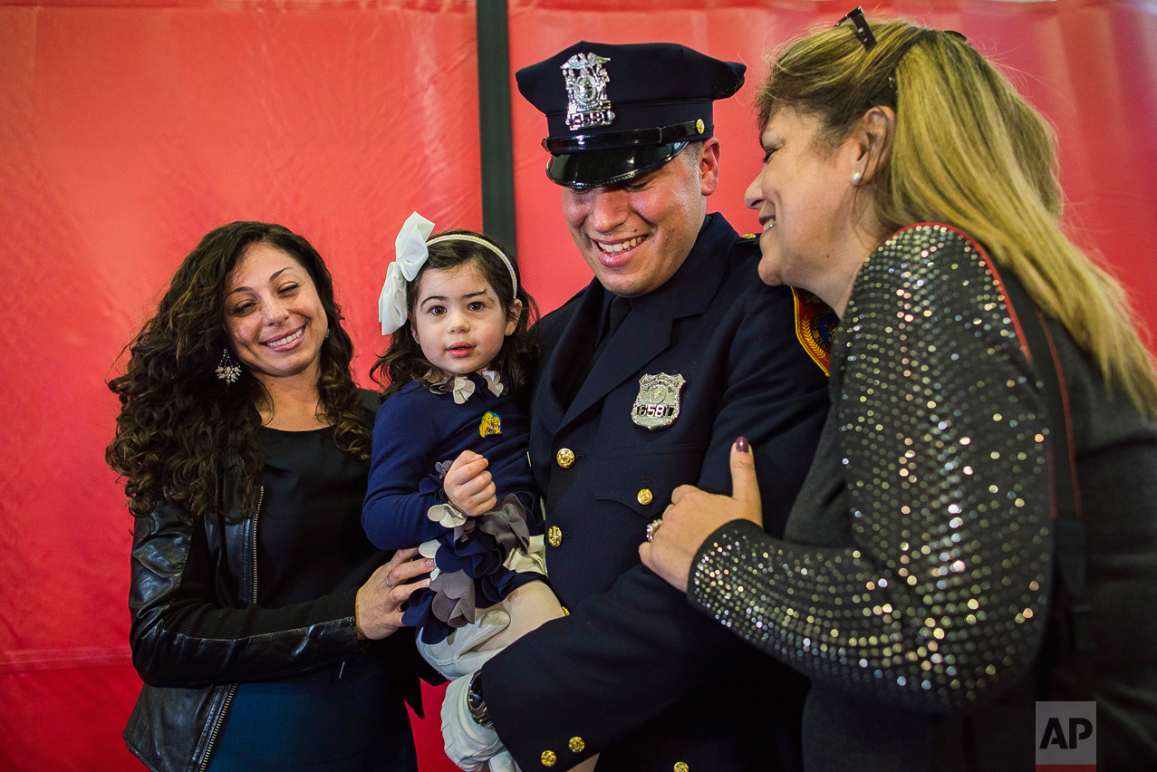 Matias Ferreira, center, celebrates with his 2-year-old daughter, his wife, left, and his mother during his graduation from the Suffolk County Police Department Academy at the Health, Sports and Education Center in Suffolk, Long Island, New York, Friday, March 24, 2017. Matias Ferreira, a former U.S. Marine Corps lance corporal who lost his legs below the knee when he stepped on a hidden explosive in Afghanistan in 2011, is joining a suburban New York police department. The 28-year-old graduated Friday from the Suffolk County Police Academy on Long Island following 29 weeks of training. (AP Photo/Andres Kudacki)