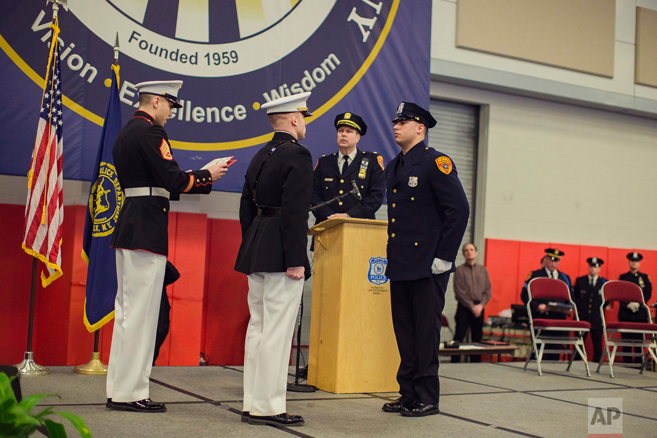 Matias Ferreira, center, receives his diploma during his graduation from the Suffolk County Police Department Academy at the Health, Sports and Education Center in Suffolk, Long Island, New York, Friday, March 24, 2017. (AP Photo/Andres Kudacki)