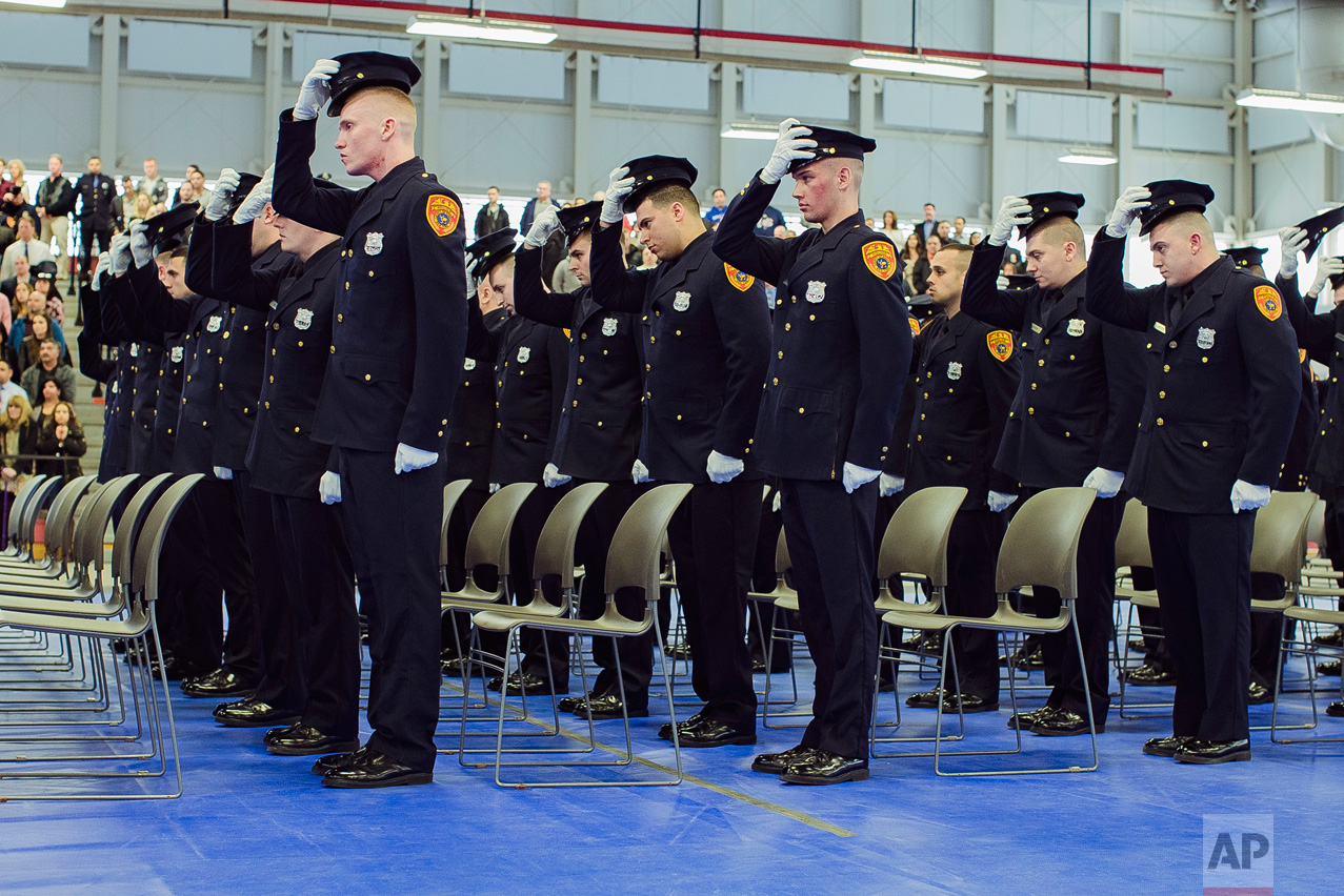 Matias Ferreira, second row, second, and his colleagues take off his hat during their graduation from the Suffolk County Police Department Academy at the Health, Sports and Education Center in Suffolk, N.Y., Friday, March 24, 2017. (AP Photo/Andres Kudacki)