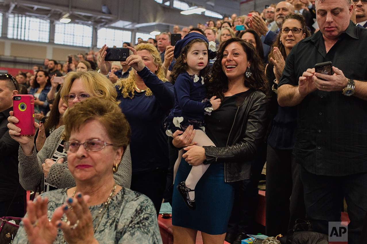 Matias Ferreira's wife, Tiffany, center right, celebrates with her daughter, her mother, bottom left, and her father, top right, during Matias' graduation from the Suffolk County Police Department Academy at the Health, Sports and Education Center in Suffolk, N.Y., Friday, March 24, 2017. (AP Photo/Andres Kudacki)