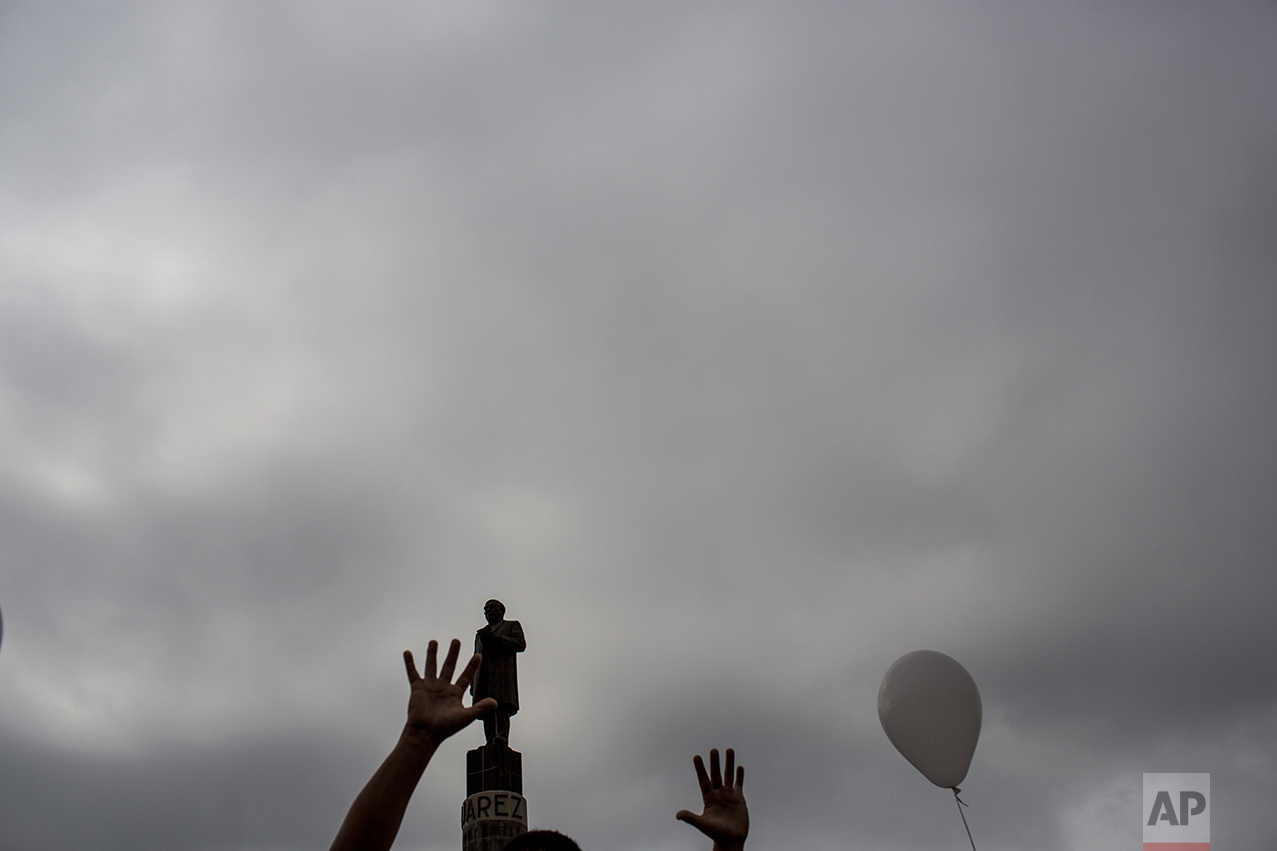  A man gestures while passing next to a statue former Mexico's President Benito Juarez during a march against violence organized by local churches in Nuevo Laredo, Tamaulipas state, Mexico, Saturday March, 25, 2017. (AP Photo/Rodrigo Abd) 