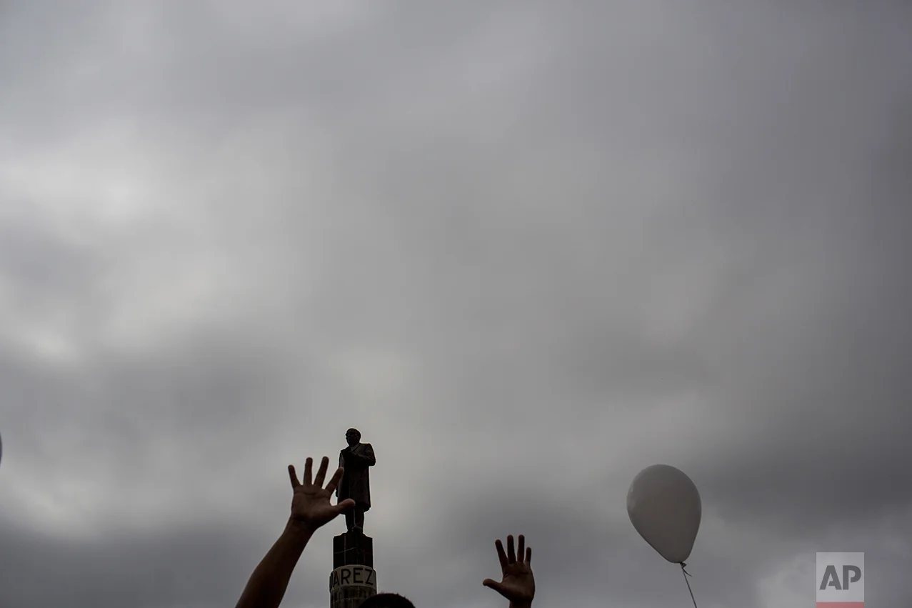 A man gestures while passing next to a statue former Mexico's President Benito Juarez during a march against violence organized by local churches in Nuevo Laredo, Tamaulipas state, Mexico, Saturday March, 25, 2017. (AP Photo/Rodrigo Abd)