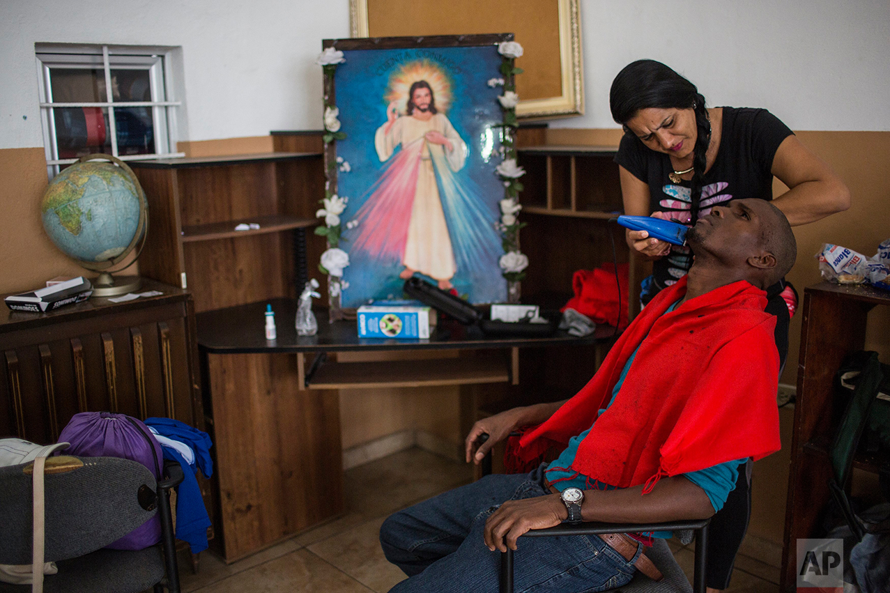 A Cuban migrant shaves her husband's beard at the migrant shelter "Casa del Migrante" in Nuevo Laredo, Tamaulipas state, Mexico, Saturday, March 25, 2017, across the border from Laredo, Texas. (AP Photo/Rodrigo Abd)