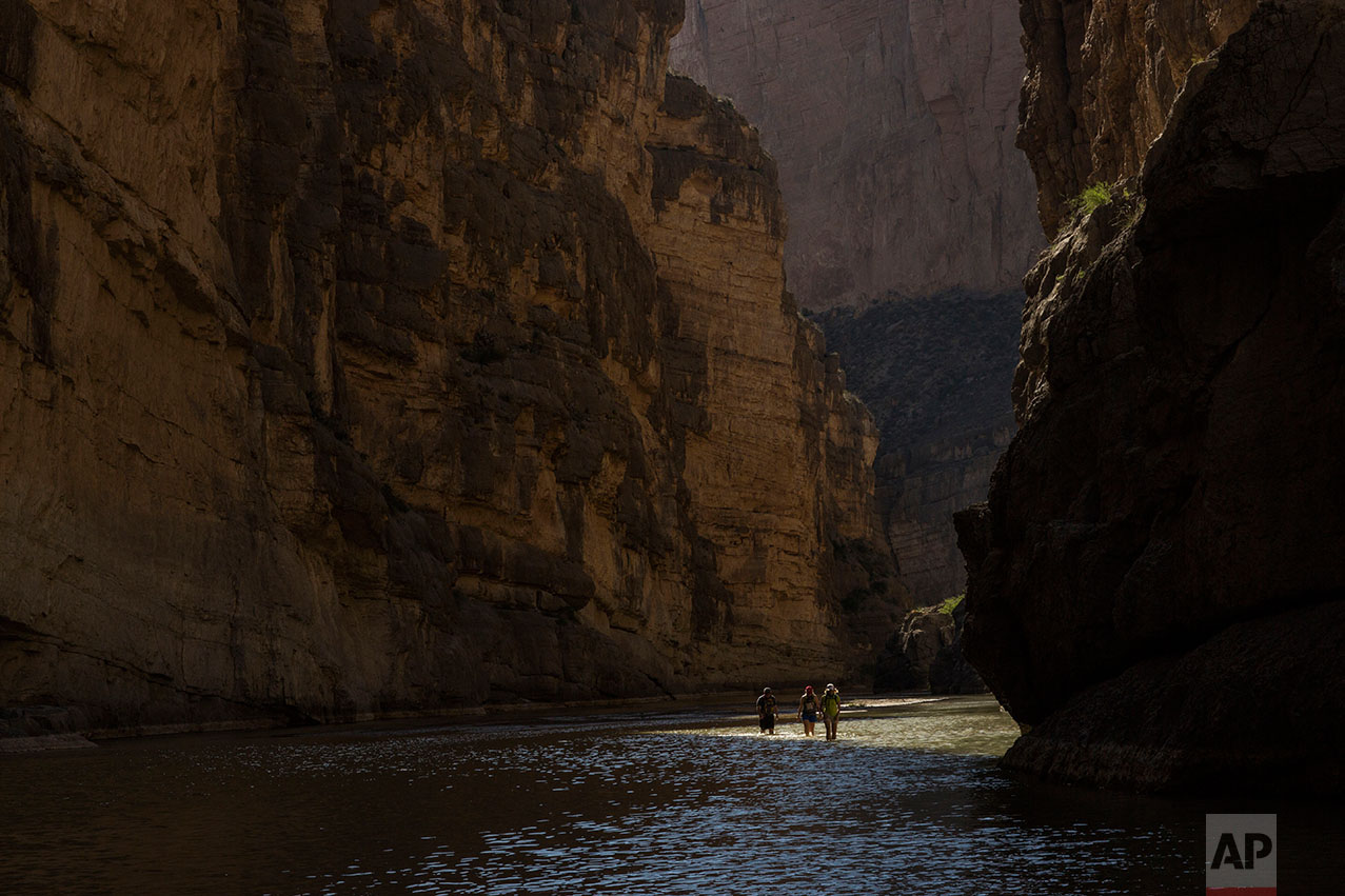 Tourists walk through Santa Elena Canyon, wading through the water of the Rio Grande, between Mexico, left, and the US, right, as they vacation at Big Bend National Park in Texas, Monday, March 27, 2017. (AP Photo/Rodrigo Abd)