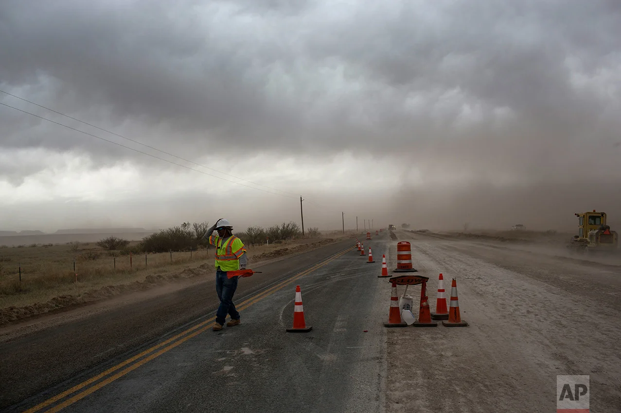 A road worker holds on to his hard hat during a dust storm near Valentine, Texas, about 20 miles from the US-Mexico border, Tuesday, March 28, 2017. (AP Photo/Rodrigo Abd)