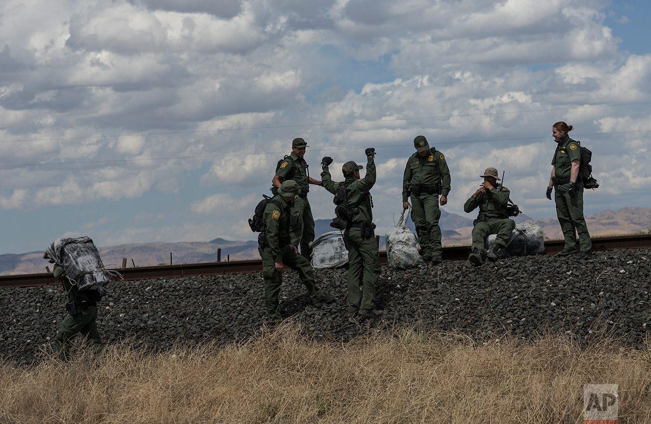  U.S. Border Patrol agents carry bales of marijuana they found along the highway near Ryan, Texas, about 20 miles from the US-Mexico border, Tuesday, March 28, 2017. One agent said "They (the smugglers) just leave it and come back another day. It's g