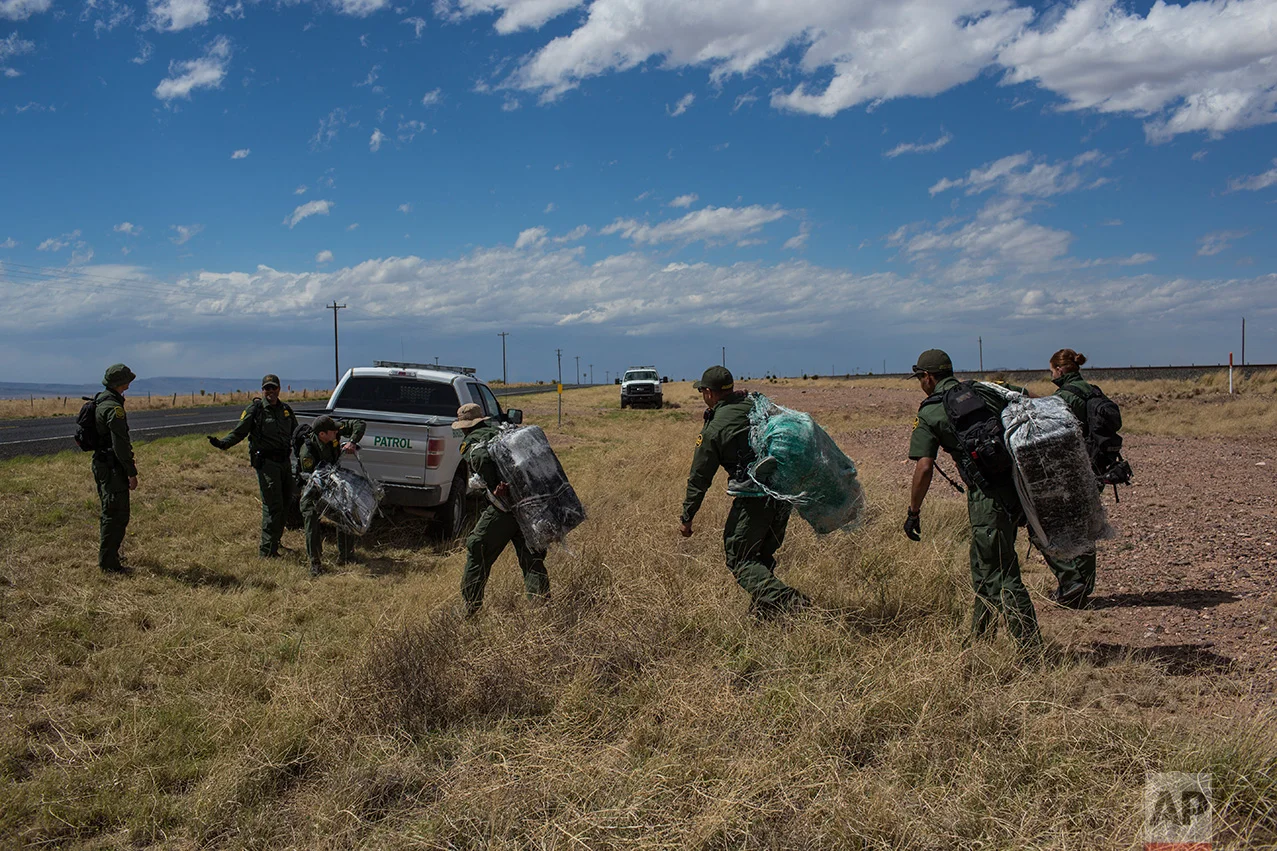 U.S. Border Patrol agents carry bales of marijuana they found along the highway near Ryan, Texas, about 20 miles from the US-Mexico border, Tuesday, March 28, 2017. One agent said "They (the smugglers) just leave it and come back another day. It's going to be sad when they come back for it." Drug interdiction is a core mission for the Border Patrol. (AP Photo/Rodrigo Abd)