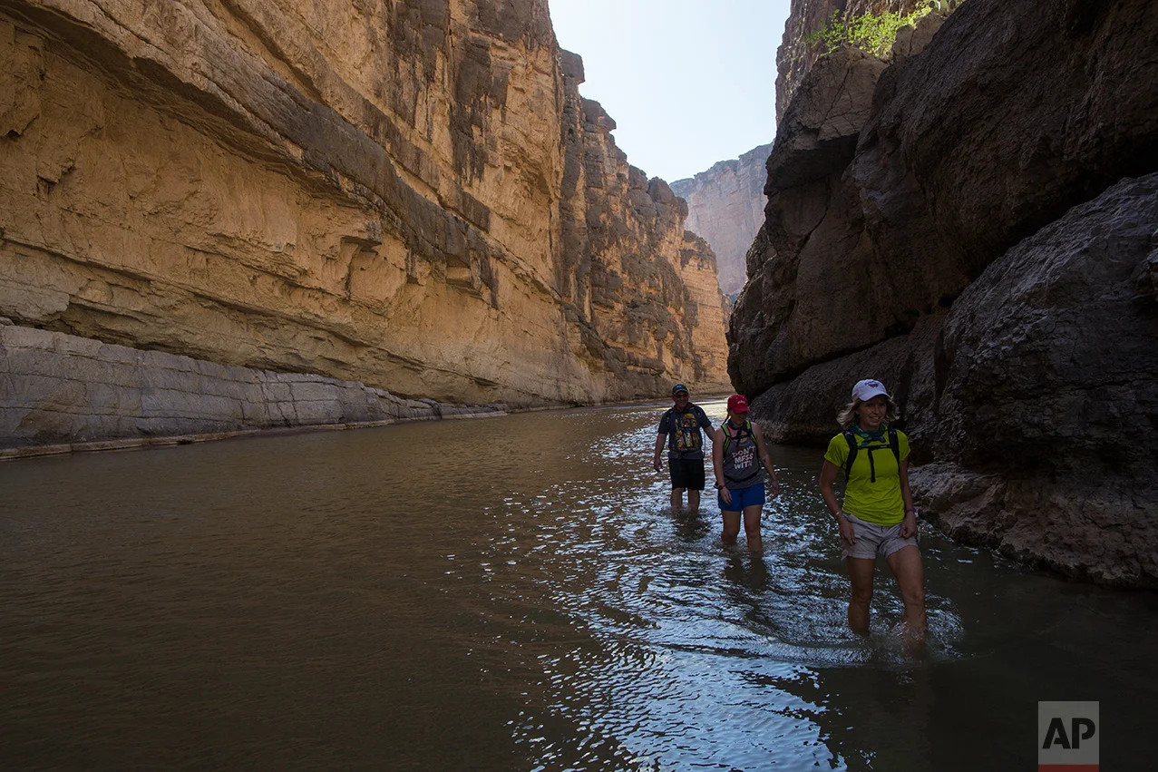 Tourists walk through Santa Elena Canyon in the water of the Rio Grande, just feet from a cliff face that is Mexico, left, as they vacation at Big Bend National Park in Texas, Monday, March 27, 2017. (AP Photo/Rodrigo Abd)
