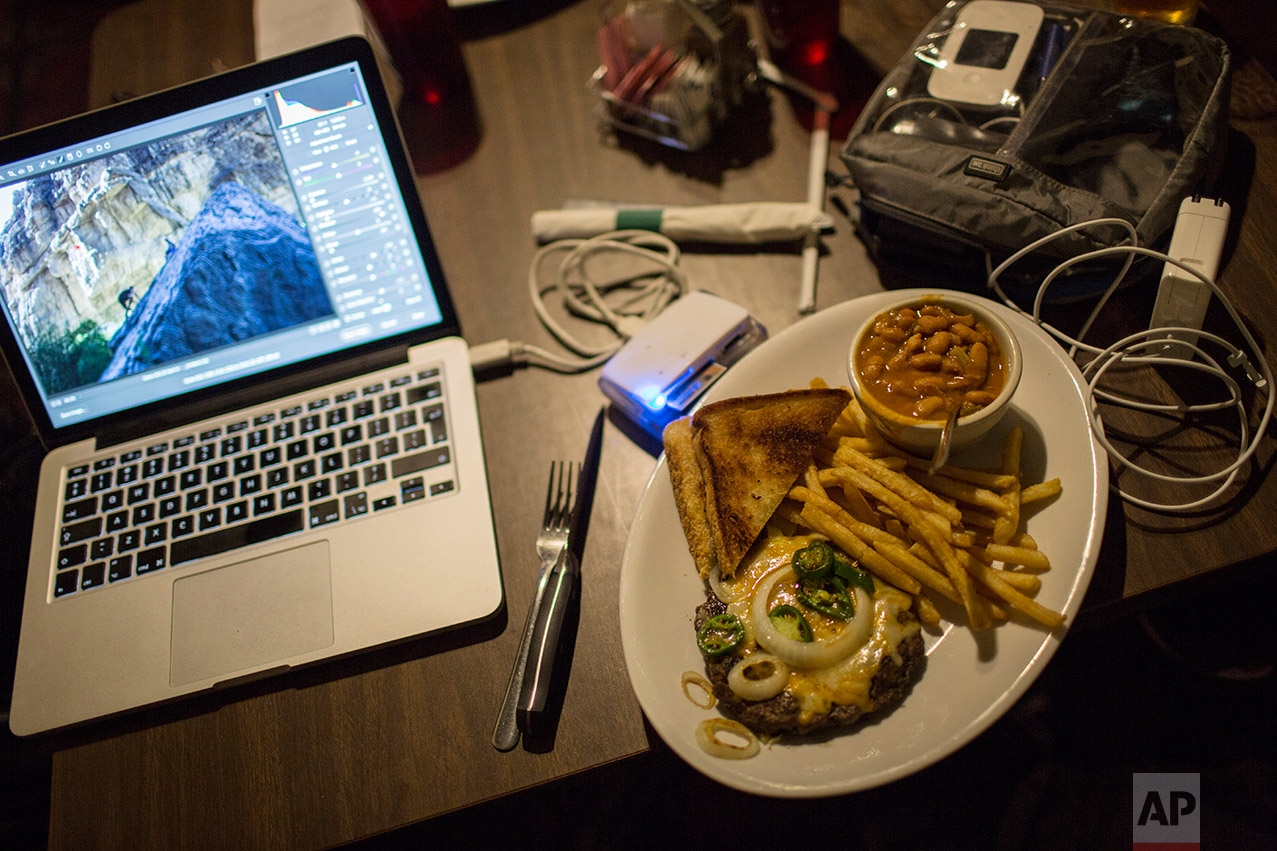  An open-faced jalapeÒo hamburger with fries, beans and toast by Rodrigo Abd's computer as he edits while eating dinner in Terlingua, Texas, near the US-Mexico border, Monday, March 27, 2017. (AP Photo/Rodrigo Abd) 