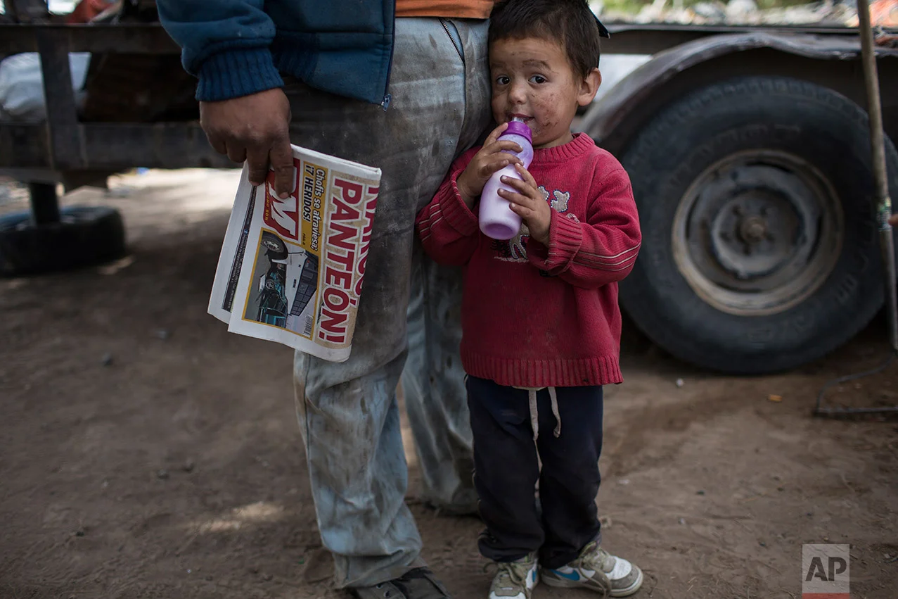 Rohan Ayala stands next to his father outside their home, meters from the fence marking the U.S.-Mexico border in Juarez Valley, Mexico, Wednesday, March 29, 201, across the border from the outskirts of El Paso, Texas. A segment of new fencing is being erected by the U.S. government outside El Paso, Texas, just west of the New Mexico state line. (AP Photo/Rodrigo Abd)