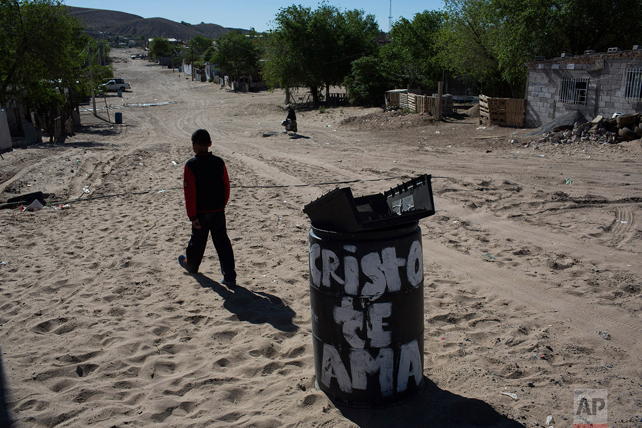  A boy walks away from the municipal garbage dump where he threw away the casing of an unusable TV, in the Anapra neighborhood of Ciudad Juarez, Mexico, Thursday, March 30, 2017, across the border from Sunland Park, New Mexico. The trash can reads in