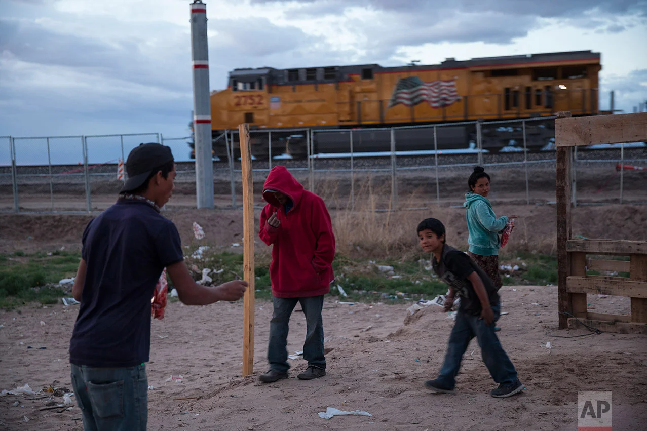 Children play a coin toss game in the sand as a train passes behind the fence marking the U.S.-Mexico border, in the Anapra neighborhood of Ciudad Juarez, Mexico, Wednesday, March 29, 2017, across the border from Sunland Park, New Mexico. There are more than 650 miles of fence, wall and vehicle barriers along the nearly 2,000-mile border. (AP Photo/Rodrigo Abd)