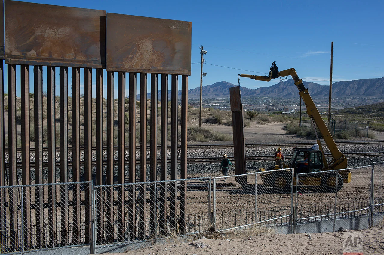 Workers use a crane to lift a segment of a new fence into place on the U.S. side of the border with Mexico, where Sunland Park, New Mexico, meets the Anapra neighborhood of Ciudad Juarez, Mexico, Thursday, March 30, 2017. Residents on the Mexico side estimate 15 to 20 panels go up daily. (AP Photo/Rodrigo Abd)
