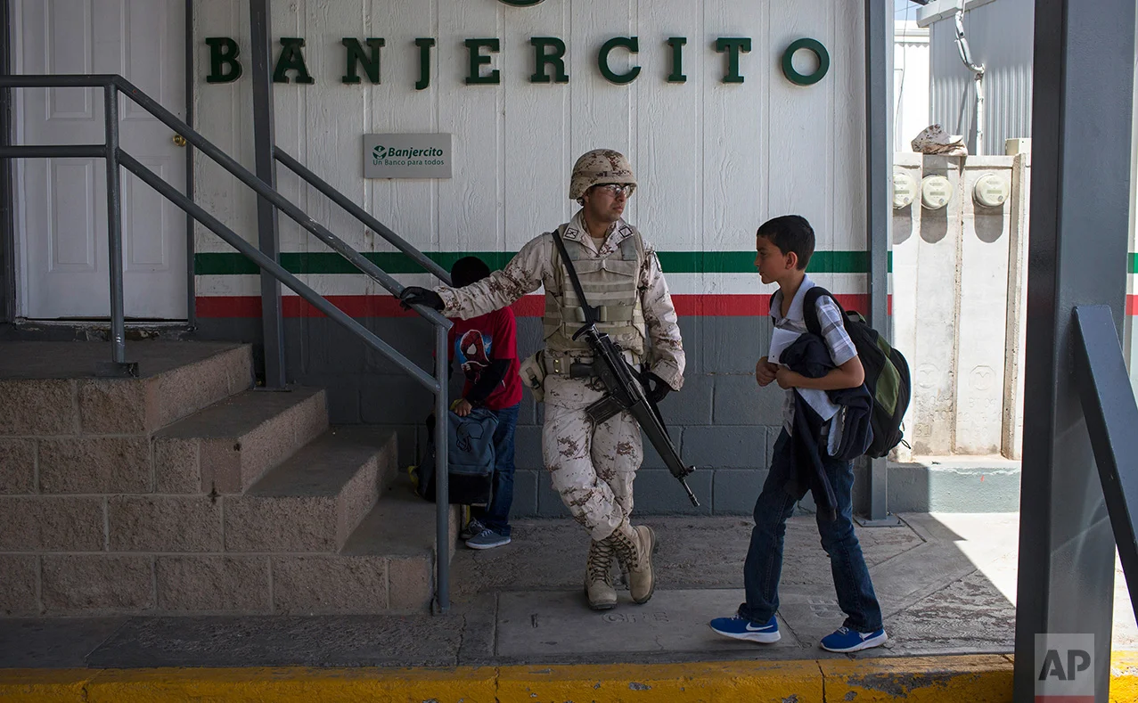 Students from Columbus Elementary School, walk next to a Mexican soldier while crossing the border from Columbus, New Mexico, US, into Palomas, Mexico, after school, Friday, March 31, 2017. (AP Photo/Rodrigo Abd)