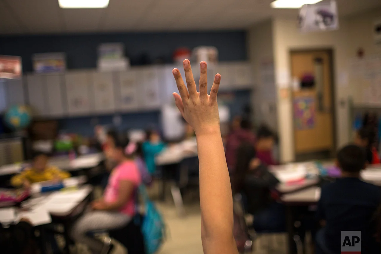 A student raises her hand during class at Columbus Elementary School, in Columbus, New Mexico, US, Friday, March 31, 2017. (AP Photo/Rodrigo Abd)