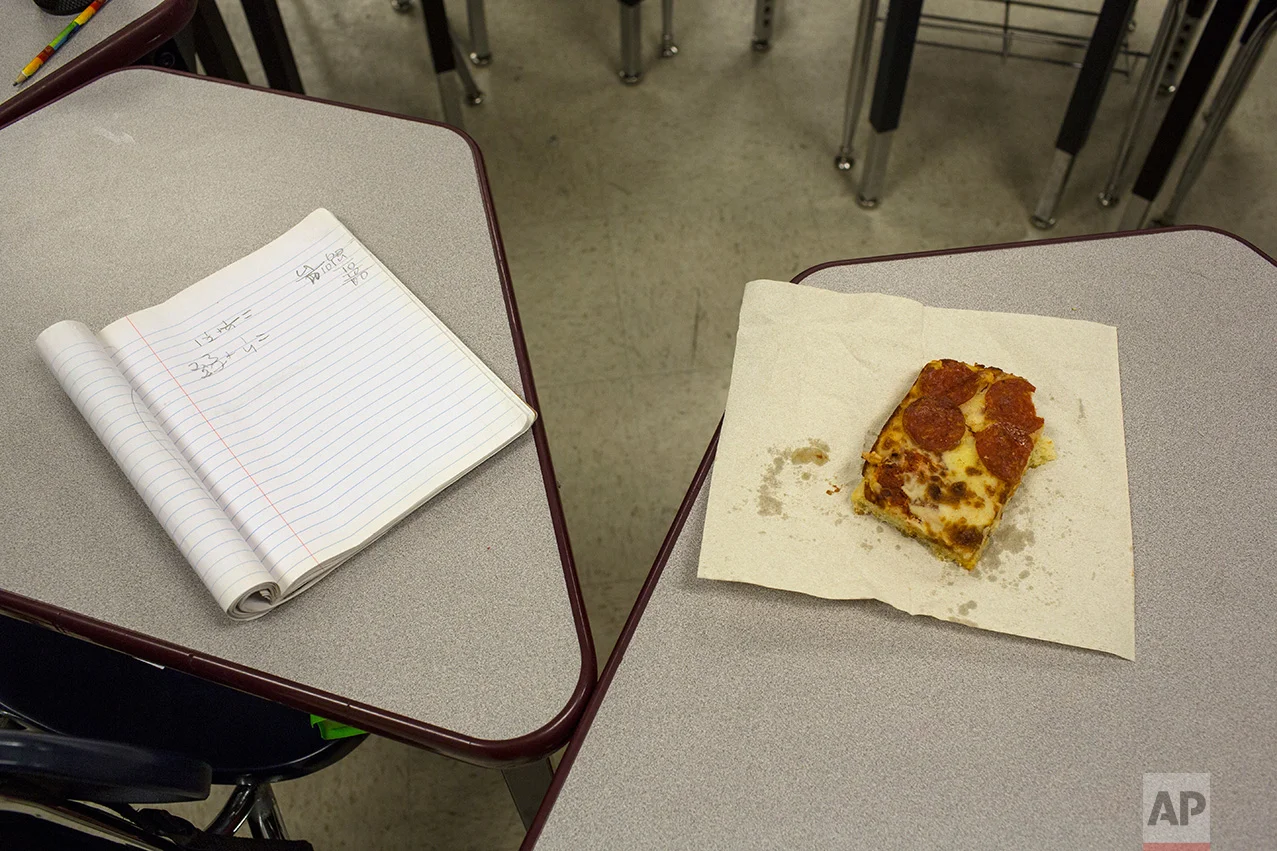 A student's slice of pizza beside a notebook in a classroom at Columbus Elementary School, in Columbus, New Mexico, US, Friday, March 31, 2017. (AP Photo/Rodrigo Abd)