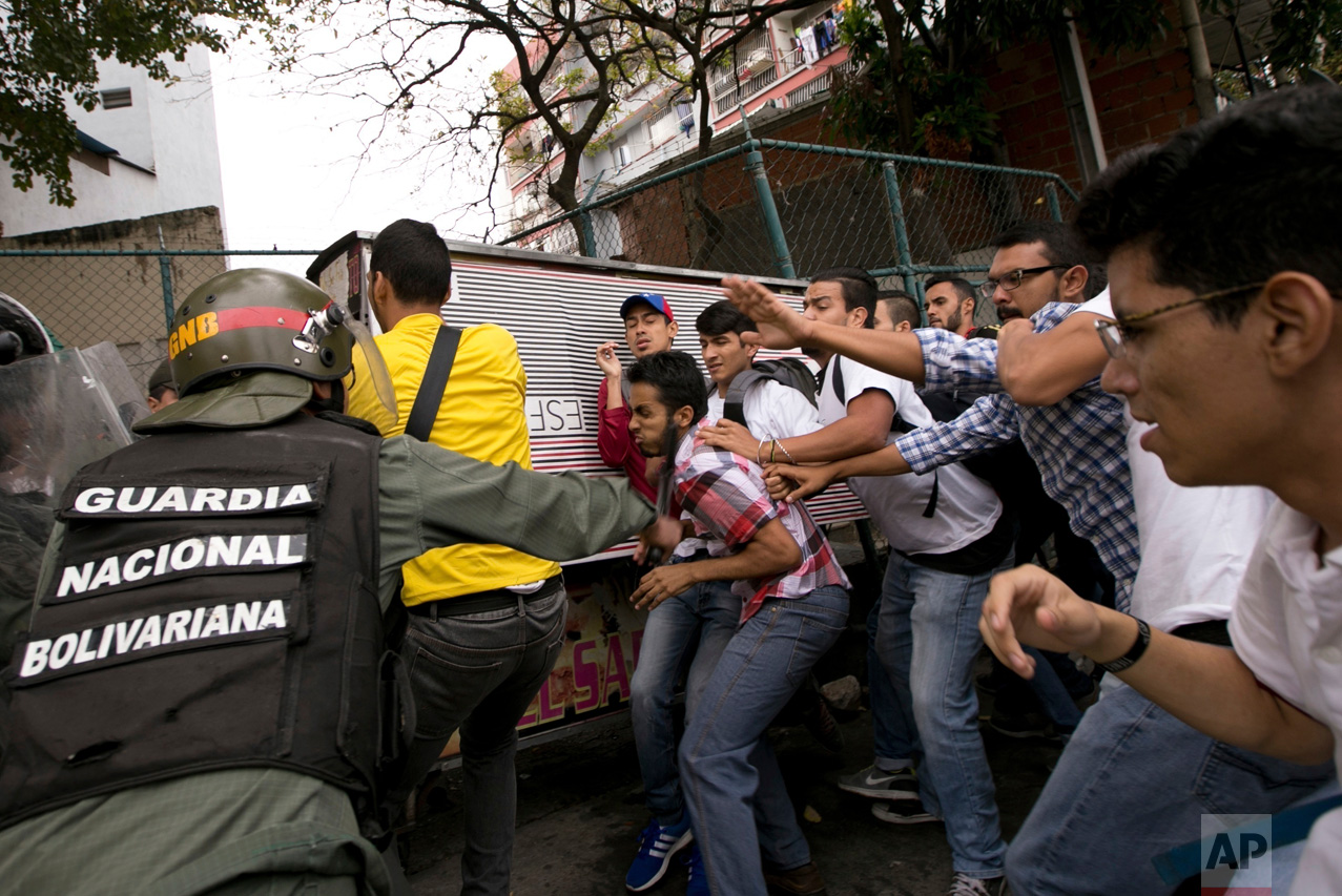 Venezuelan Bolivarian National guard officers are confronted by university students during a protest outside of the Supreme Court in Caracas, Venezuela, Friday, March 31, 2017. Venezuelans have been thrust into a new round of political turbulence after the government-stacked Supreme Court gutted congress of its last vestiges of power, drawing widespread condemnation from foreign governments and sparking protests in the capital. (AP Photo/Ariana Cubillos)