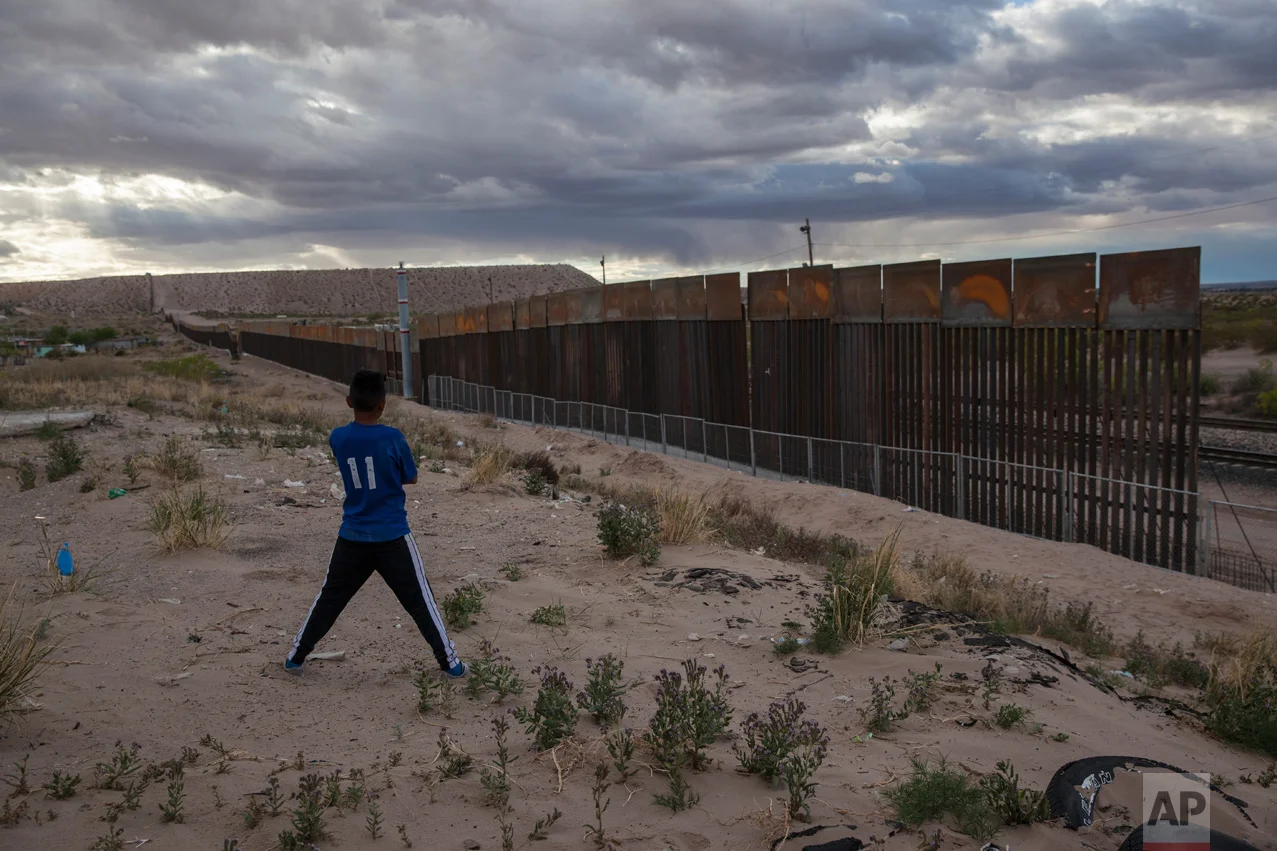 A boy looks at a new, taller fence being built along U.S.-Mexico border, replacing the shorter, gray fence in front of it, in the Anapra neighborhood of Ciudad Juarez, Mexico, Wednesday, March 29, 2017, across the border from Sunland Park, N.M. (AP Photo/Rodrigo Abd)