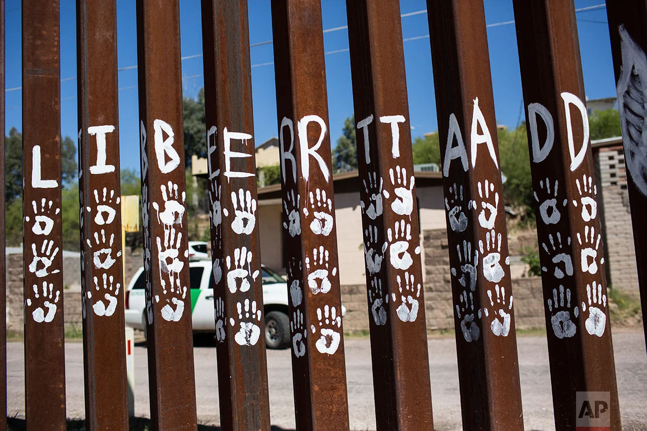 Handprints and the Spanish word for "Liberty" mark slats of the US-Mexico border fence in Nogales, Mexico, Sunday, April 2, 2017. (AP Photo/Rodrigo Abd)
