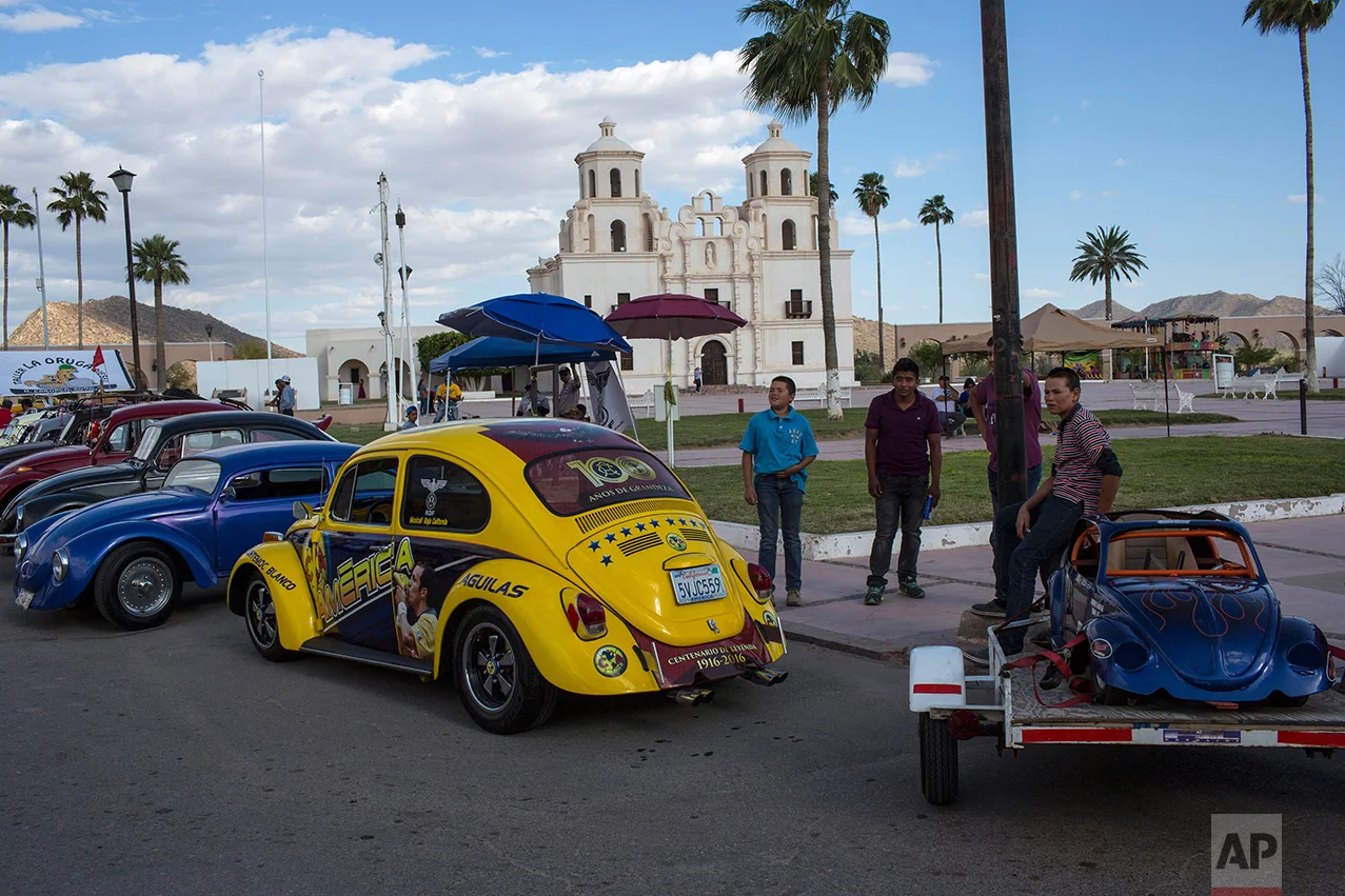 People gather for a car show featuring Volkswagen Beetles, known as 'bochos' by locals, in Caborca, in the Mexican state of Sonora, Saturday, April 1, 2017. Caborca lies in traditional tribal lands of the Tohono O'odham indigenous people, a region that straddles the U.S.-Mexico border in the states of Arizona and Sonora.(AP Photo/Rodrigo Abd)