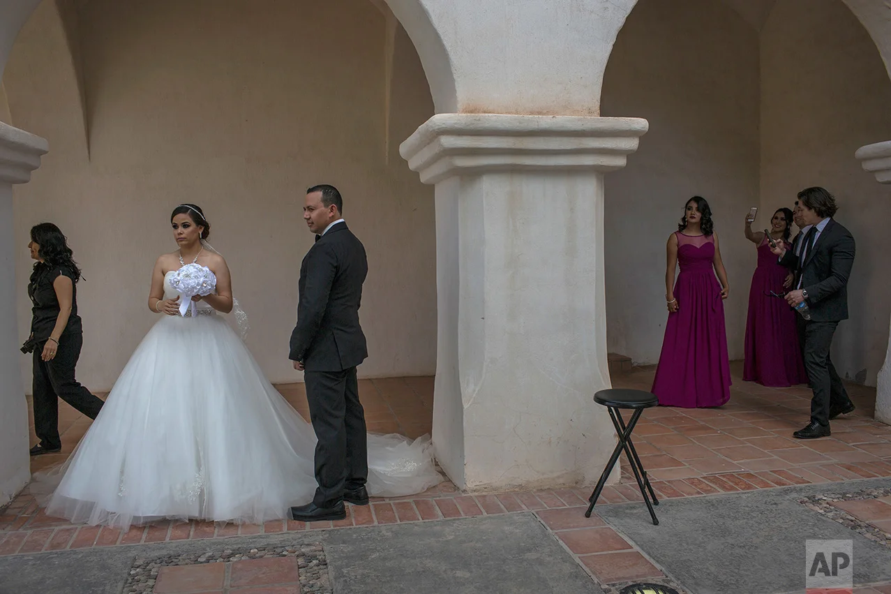 Newlyweds Aldo and Brenda Norris wait for their wedding photographer outside a church in Caborca, Sonora state, Mexico, Saturday, April 1, 2017. Caborca lies in traditional tribal lands of the Tohono O'odham indigenous people, a region that straddles the U.S.-Mexico border in the states of Arizona and Sonora. (AP Photo/Rodrigo Abd)