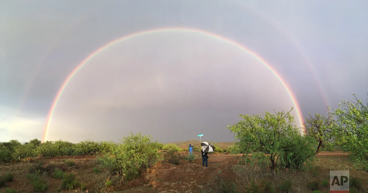 Video journalist Brian Skoloff, left, and AP photographer Rodrigo Abd see a double rainbow on the outskirts of Sasabe, in the Mexican state of Sonora, near the border with Arizona, April 1, 2017. (AP Photo/Christopher Sherman)