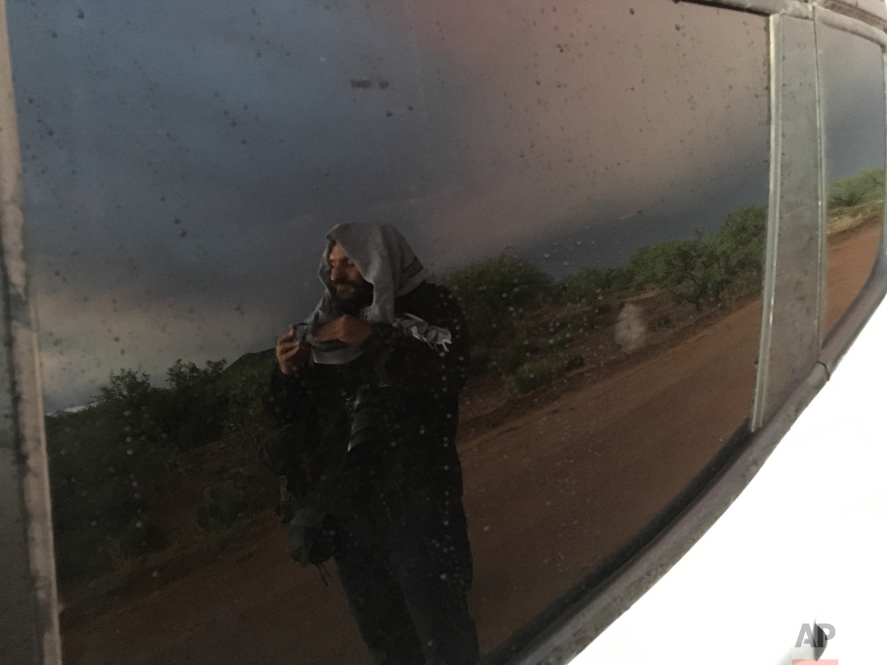  AP photographer Rodrigo Abd is reflected in a car window as he cleans his lens before seeing a double rainbow on the outskirts of Sasabe, in the Mexican state of Sonora, near the border with Arizona, April 1, 2017. (AP Photo/Christopher Sherman) 