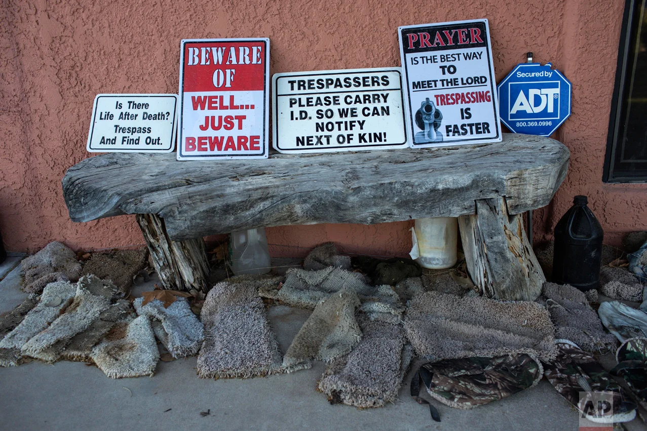 Signs warning trespassers line a wooden bench surrounded by makeshift slip-ons known as "carpet shoes" on the porch of rancher Jim Chilton, in Arivaca, Ariz., Sunday, April 2, 2017. Chilton, who finds the slip-ons abandoned on his property, says they are worn by people illegally crossing the border as a way to keep authorities from finding their tracks. (AP Photo/Rodrigo Abd)
