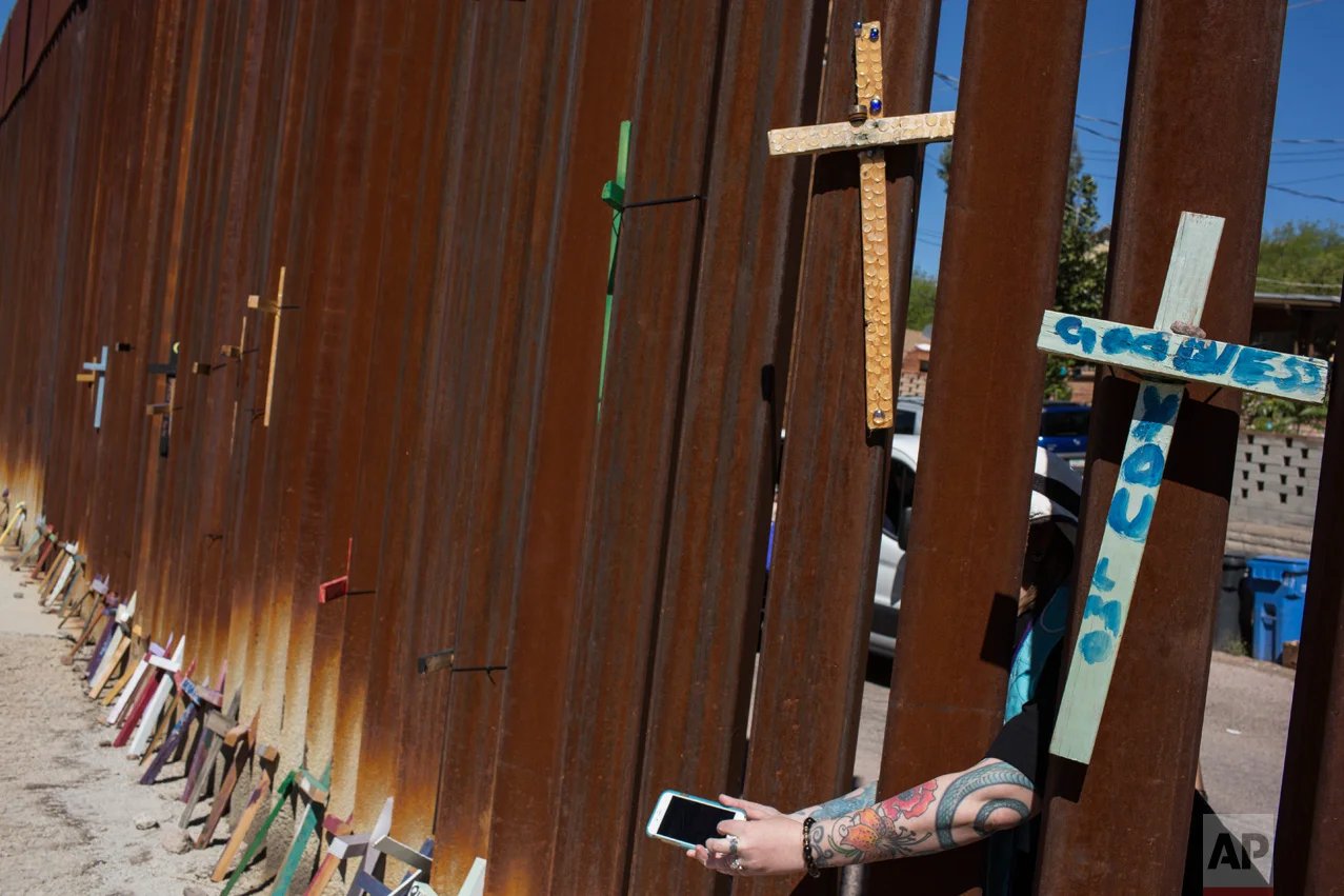 Rachel Baker, a Unitarian minister from Las Vegas, Nev., maneuvers to take a selfie through the US-Mexico border fence while standing in Nogales, Ariz., during a solidarity march, Sunday, April 2, 2017. (AP Photo/Rodrigo Abd)