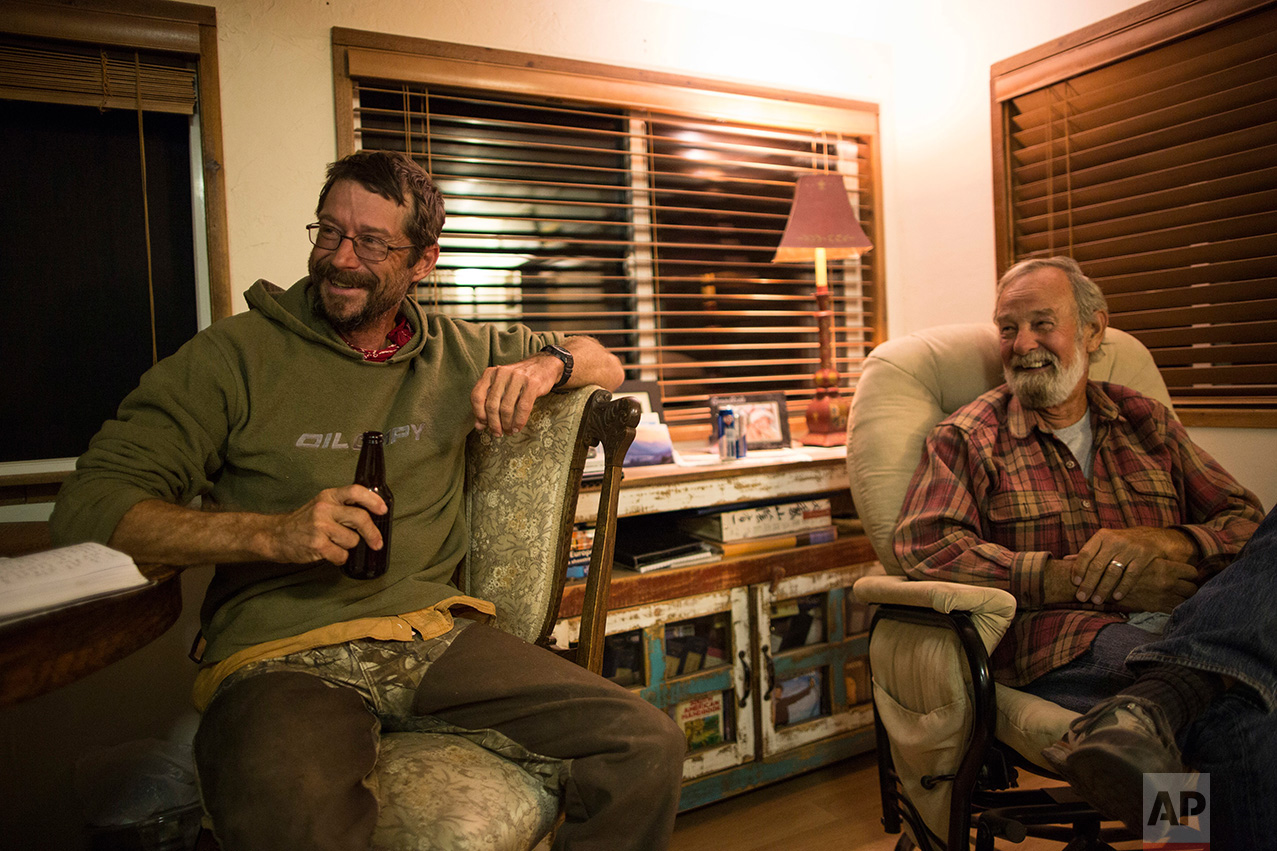 Mark Hainds of Andalusia, Alabama, left, enjoys a beer at the end of a day's walk in the home of archeologist Rick Martynec in Why, Arizona, Monday, April 3, 2017. (AP Photo/Rodrigo Abd)