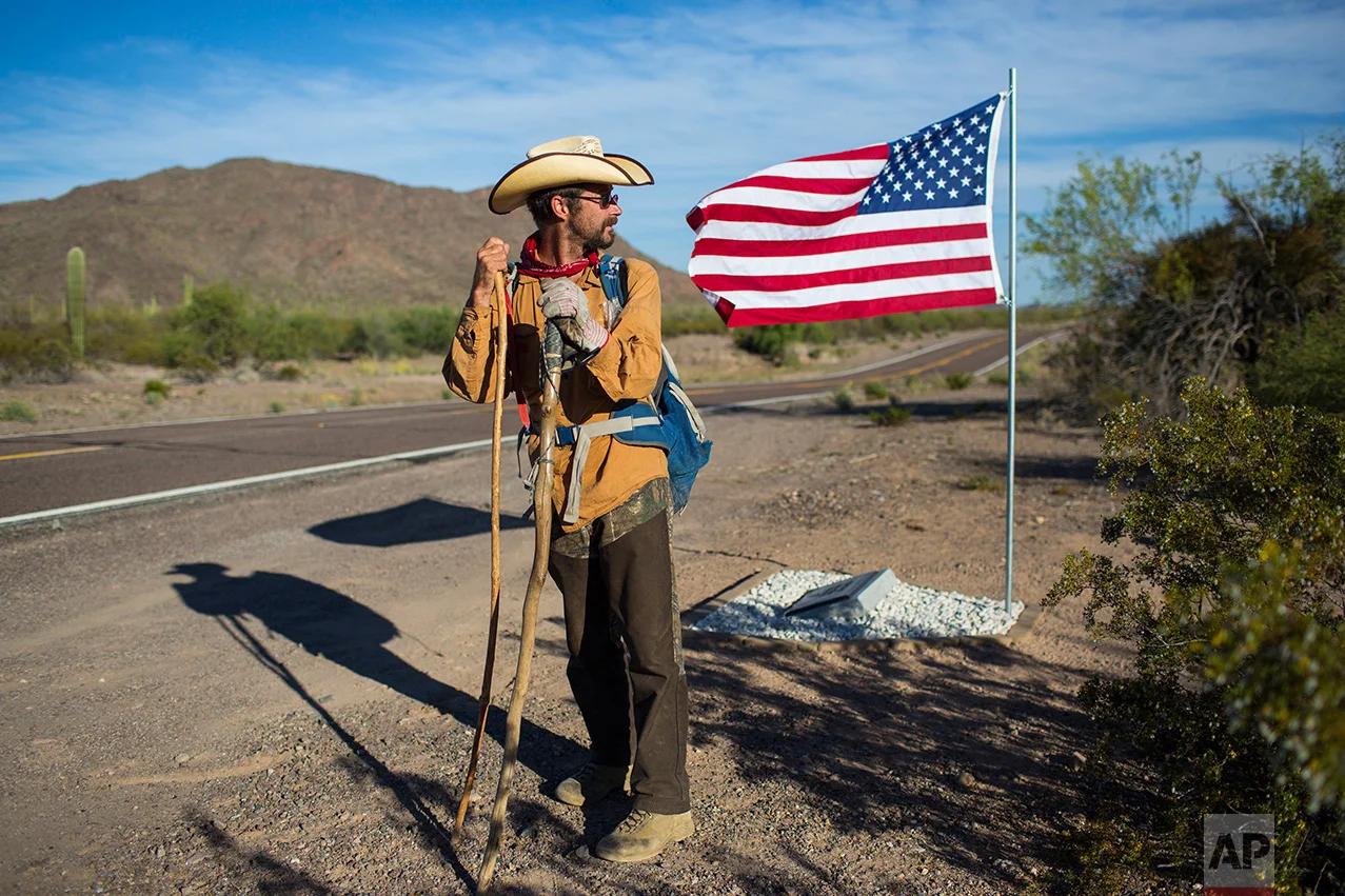 Mark Hainds of Andalusia, Alabama, stands next to a road memorial for a Border Patrol agent killed in a car accident, near Why, Ariz., Monday, April 3, 2017. Hainds is attempting to walk the length of the U.S.-Mexico border. (AP Photo/Rodrigo Abd)