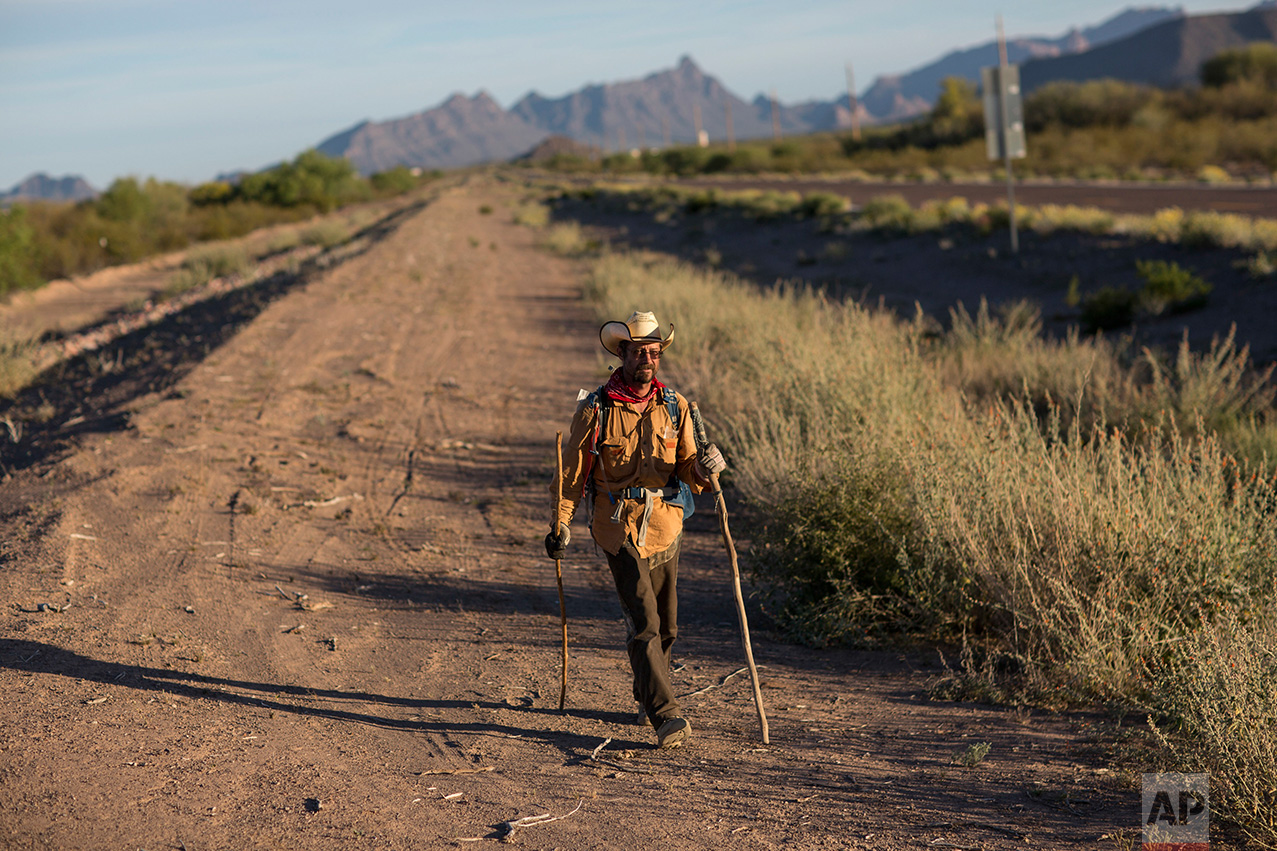 Mark Hainds, a 48-year-old junior community college forestry professor from Andalusia, Alabama, walks on the shoulder of a road near Why, Ariz., Monday, April 3, 2017. (AP Photo/Rodrigo Abd)